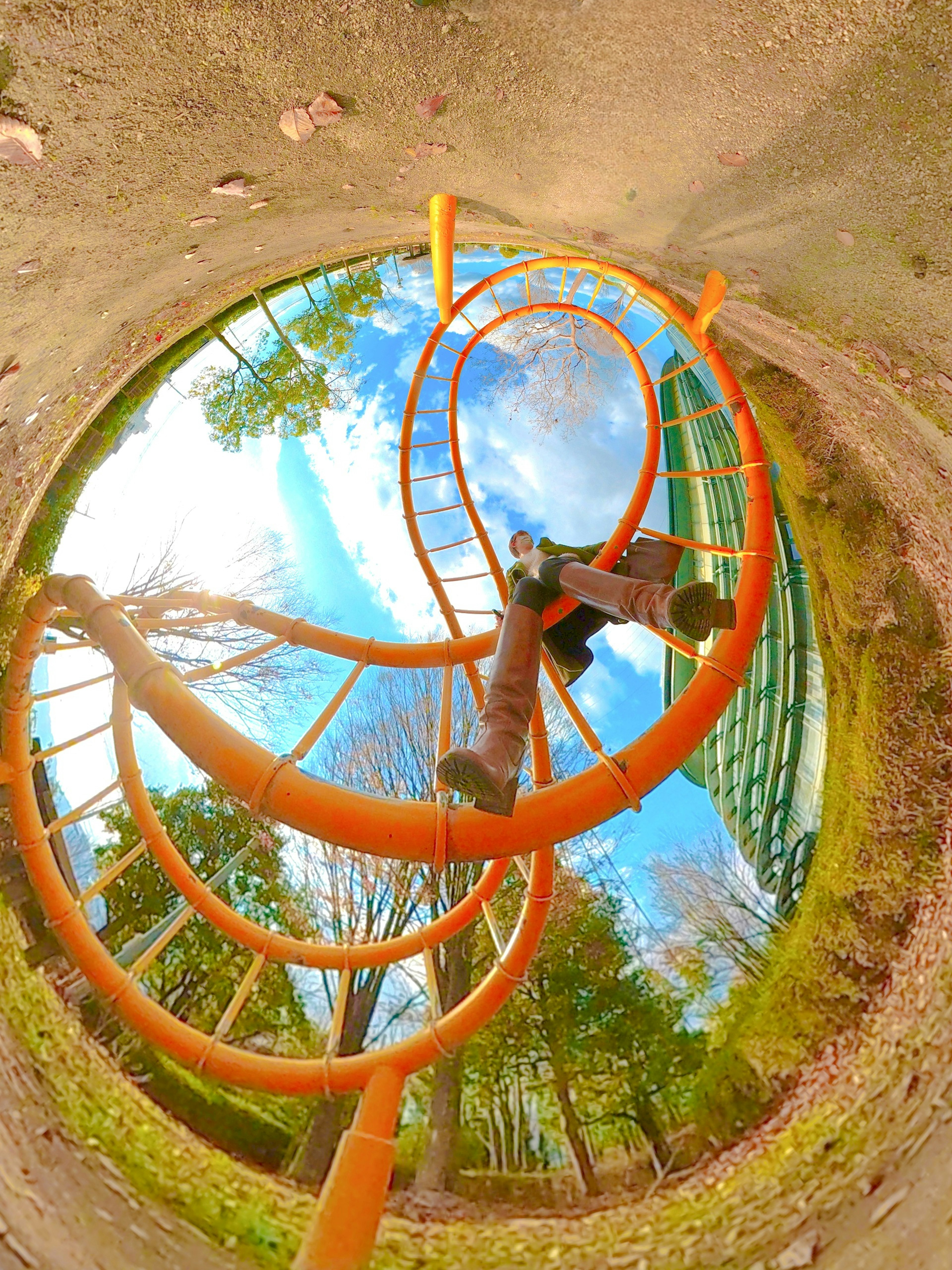 360-Grad-Blick auf einen Park mit orangefarbenen Spielgeräten und blauem Himmel