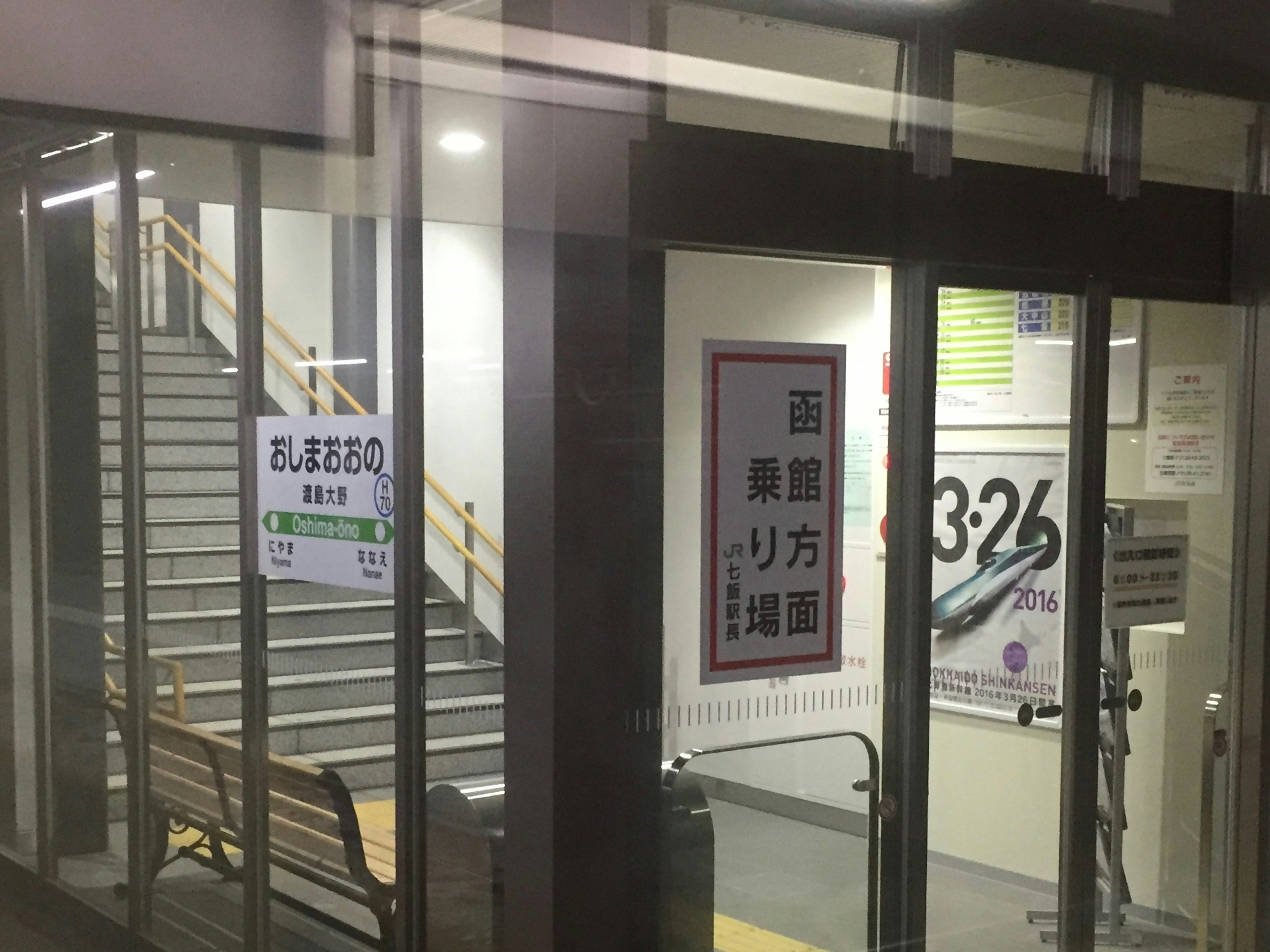 Vista exterior de un edificio con puertas de vidrio y escaleras que presentan carteles coloridos