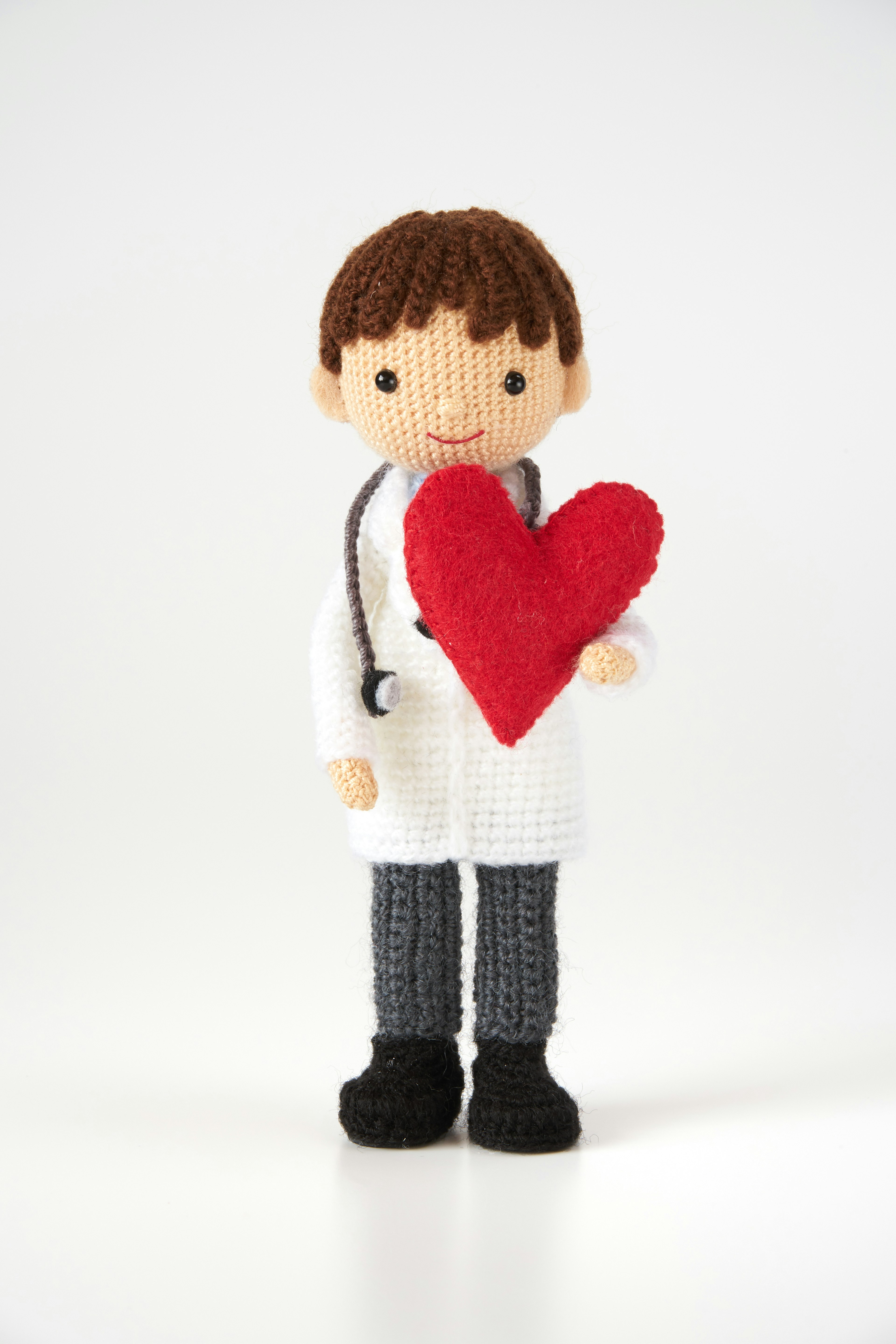 A doll in a white coat holding a red heart