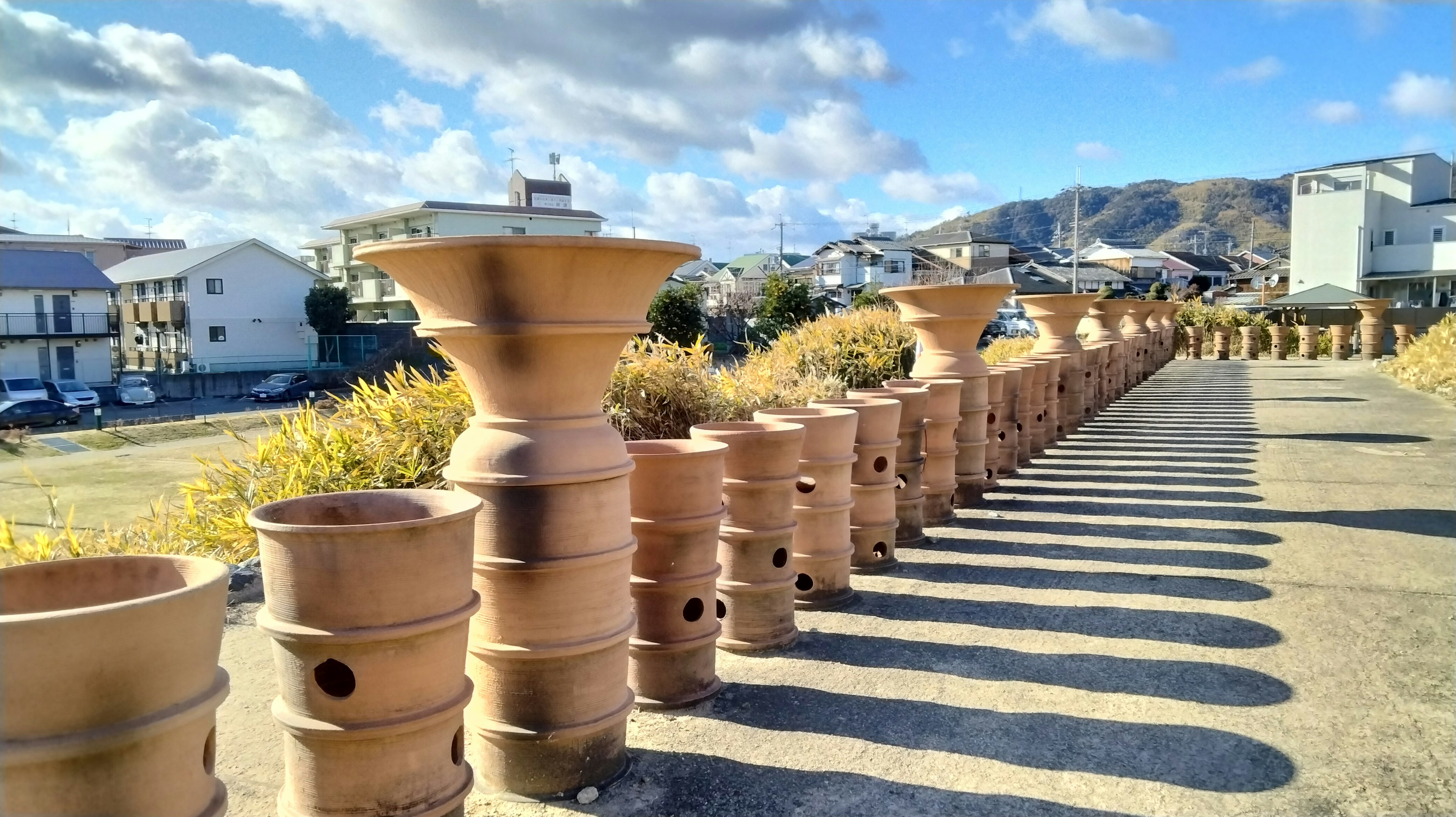 Path lined with ceramic vases under a bright sky