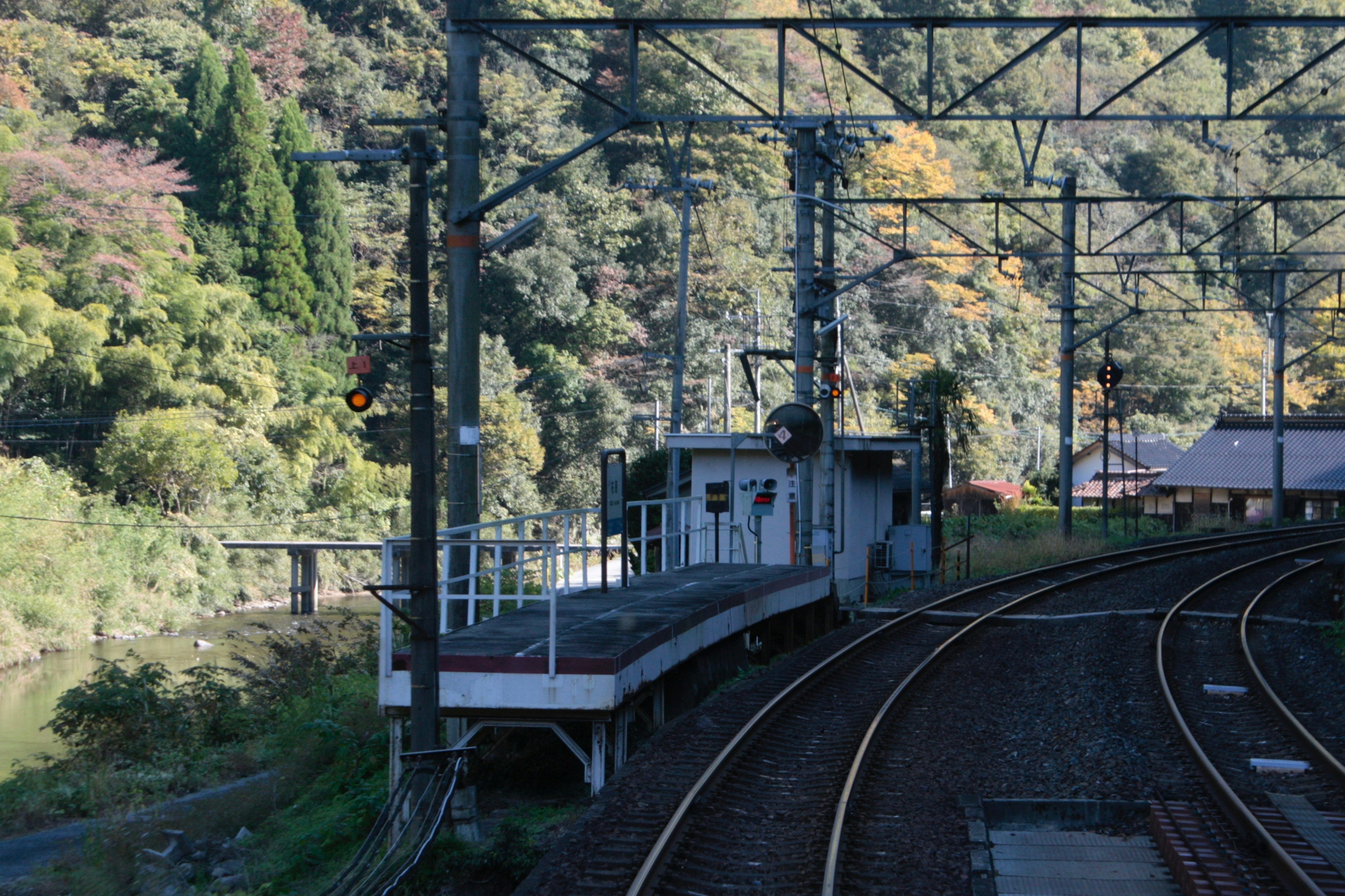 Piattaforma della stazione ferroviaria con binari curvi e paesaggio verdeggiante circostante