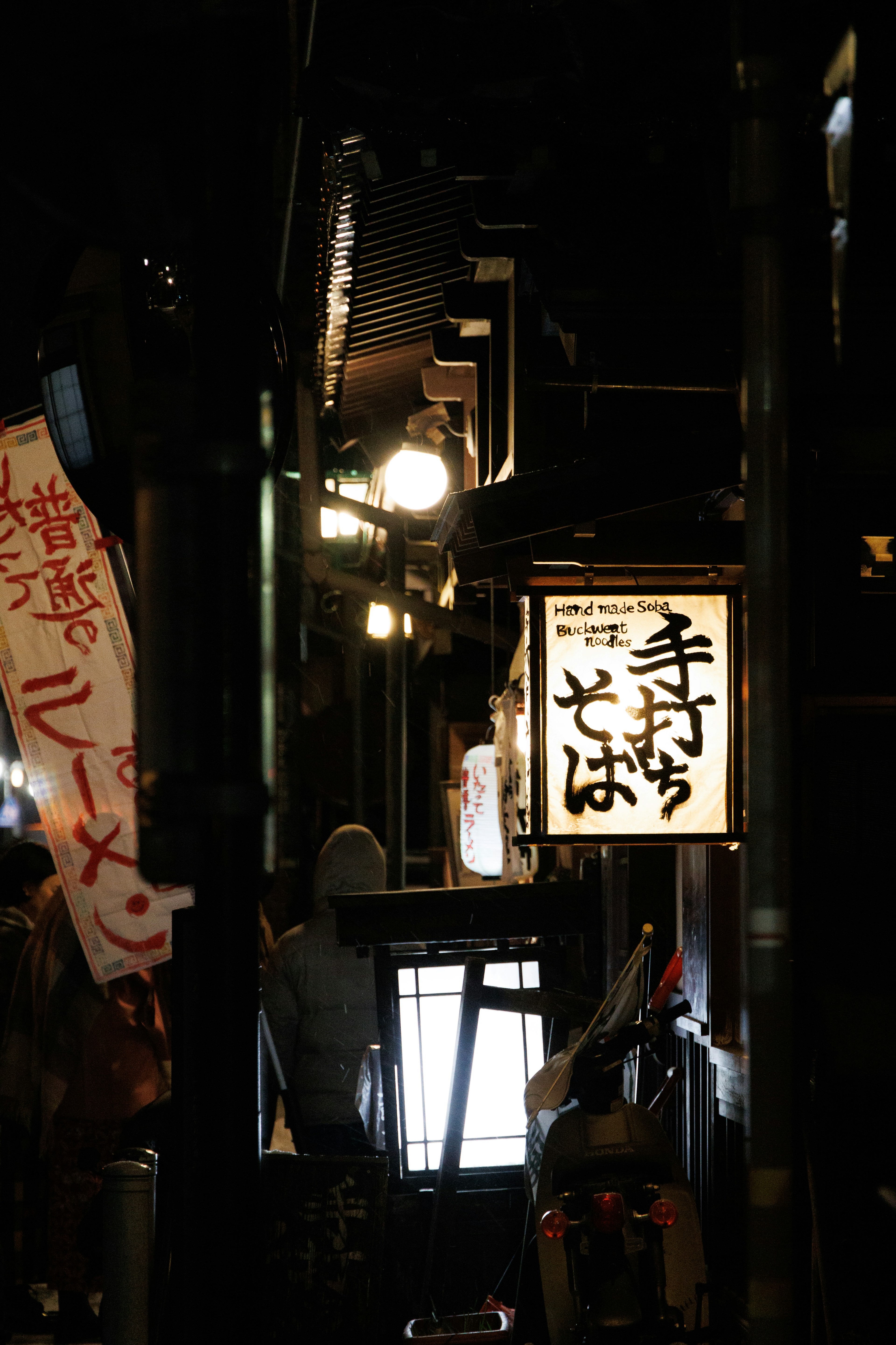 狭い路地にある手打ちそばの看板と灯り