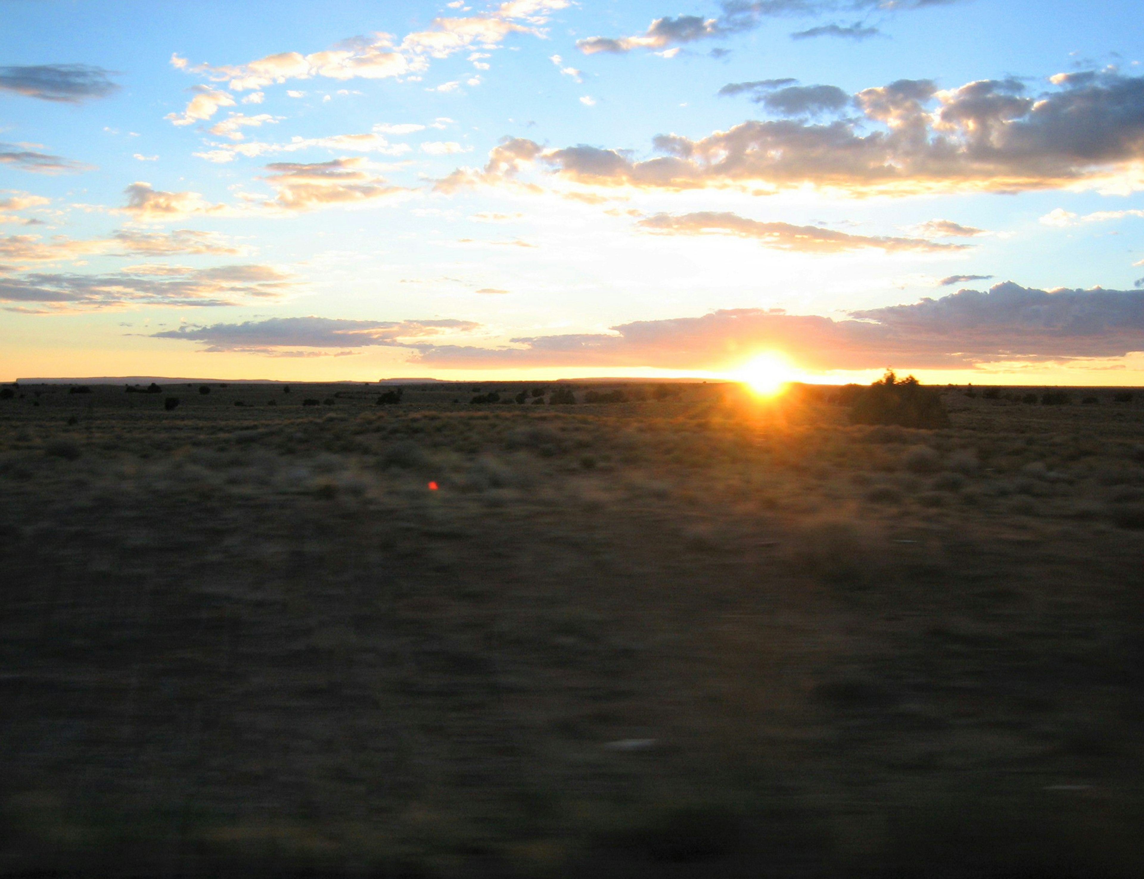 Amplio paisaje con el atardecer en el horizonte