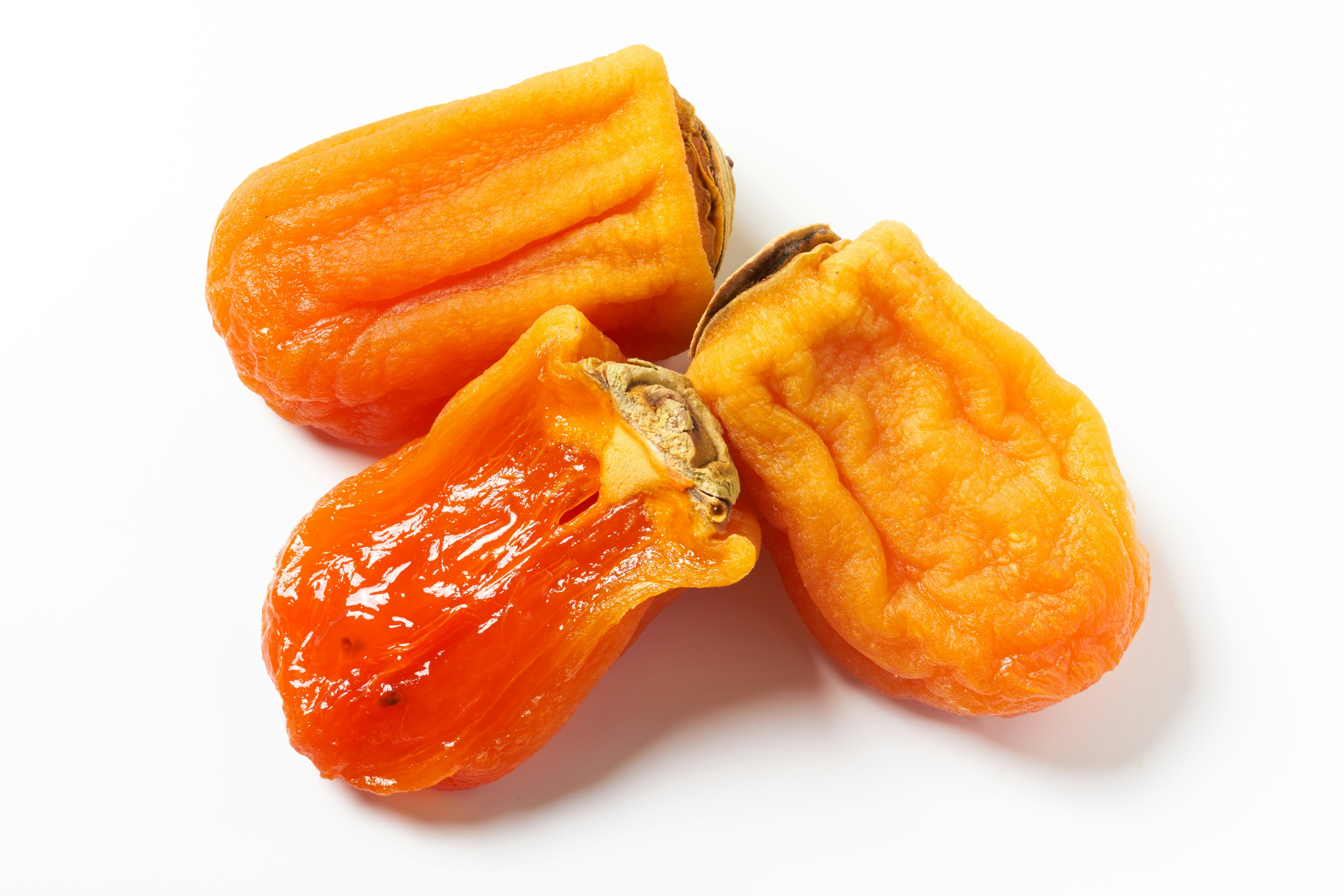 Three orange dried fruits placed on a white background