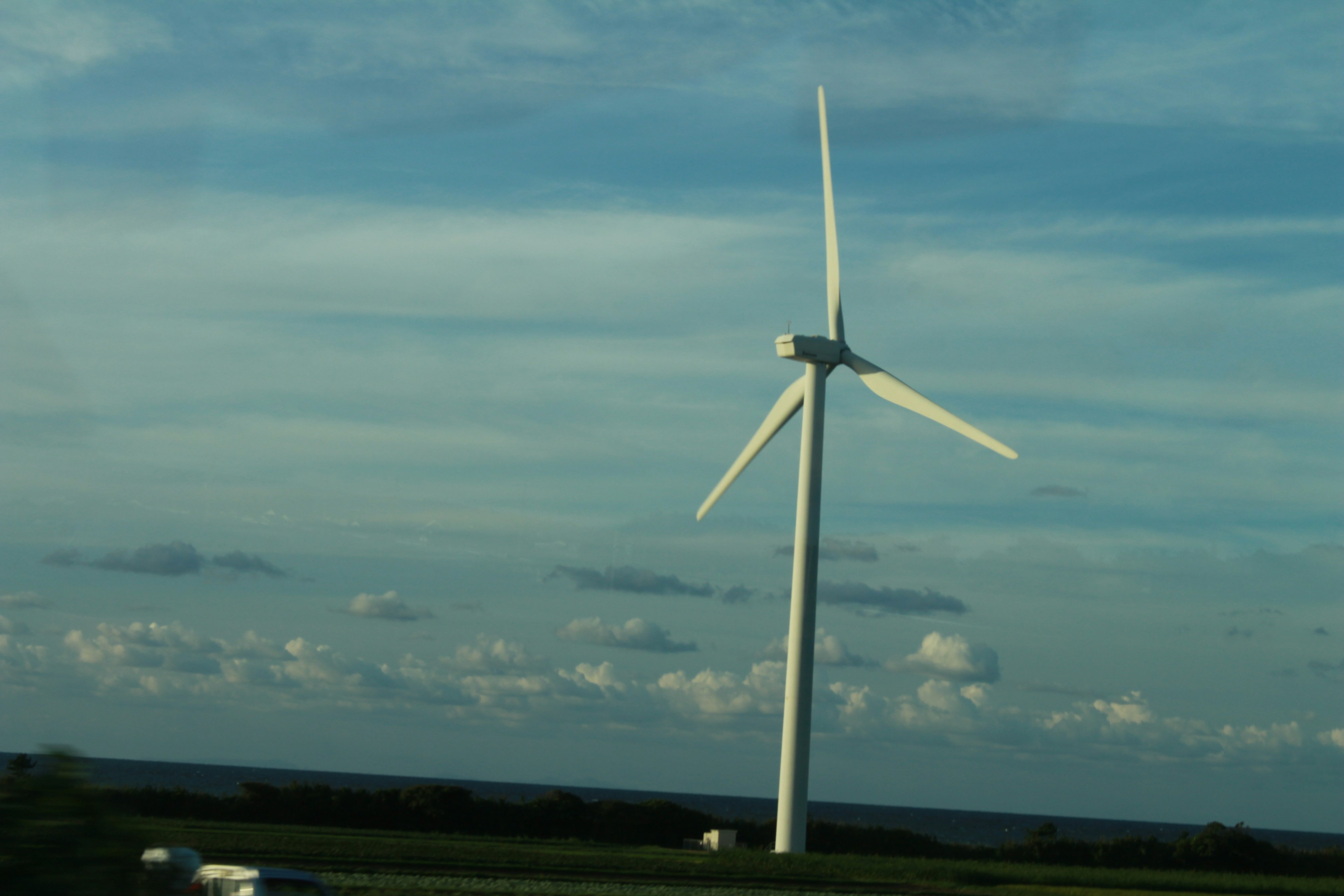 Una turbina eolica che si erge sotto un cielo azzurro con nuvole