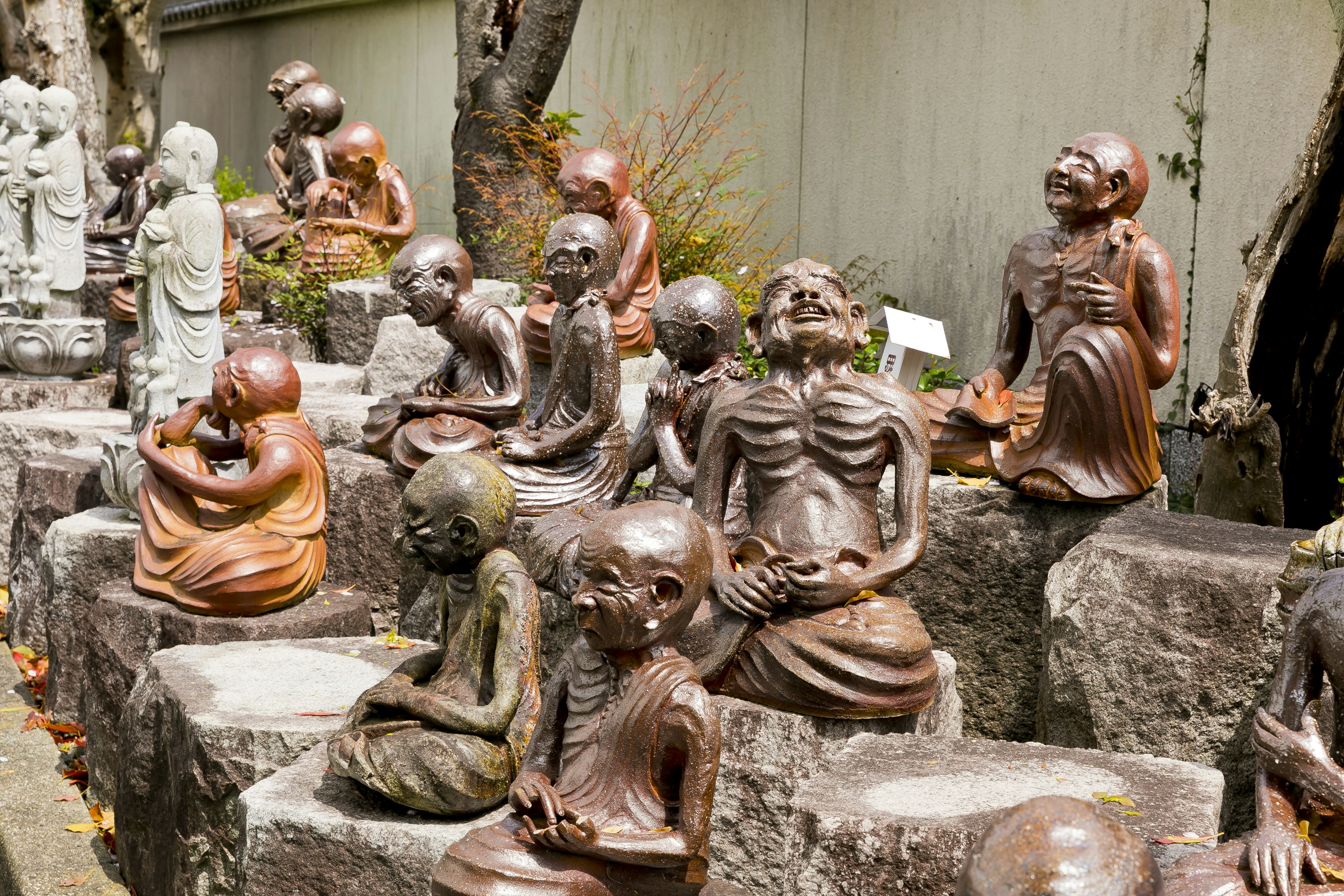 Eine Sammlung von Bronzestatuen, die verschiedene sitzende Figuren in einem Garten darstellen