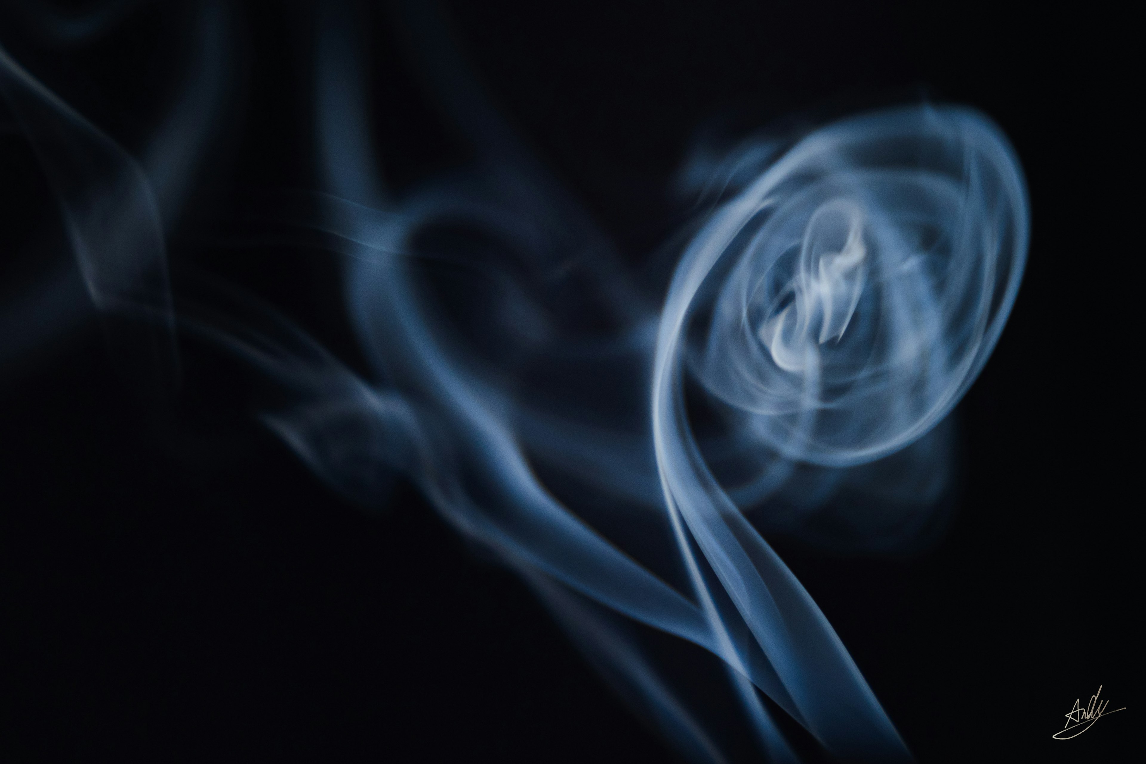 Abstract image of swirling blue smoke against a black background