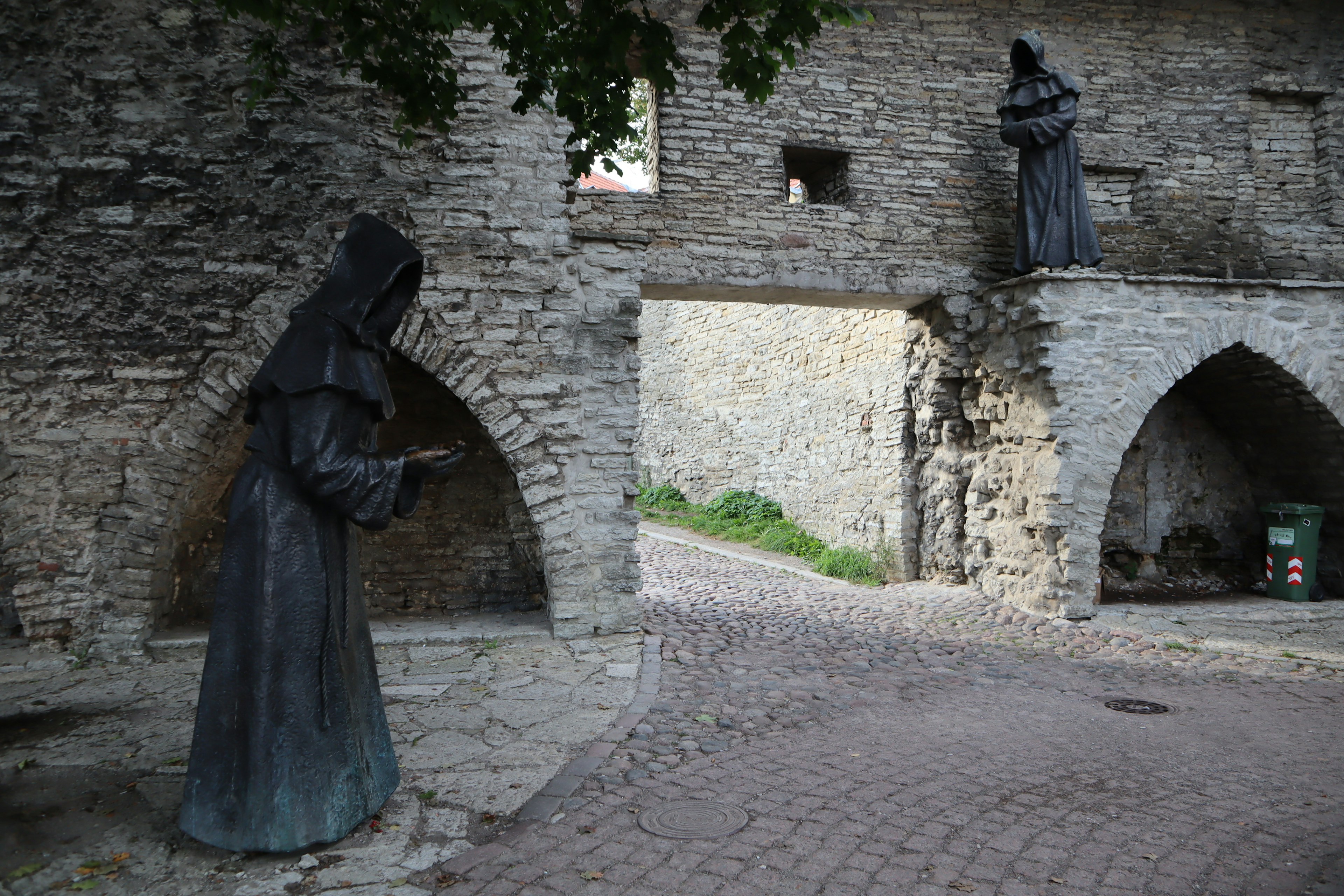 Scene of two bronze statues standing between stone walls