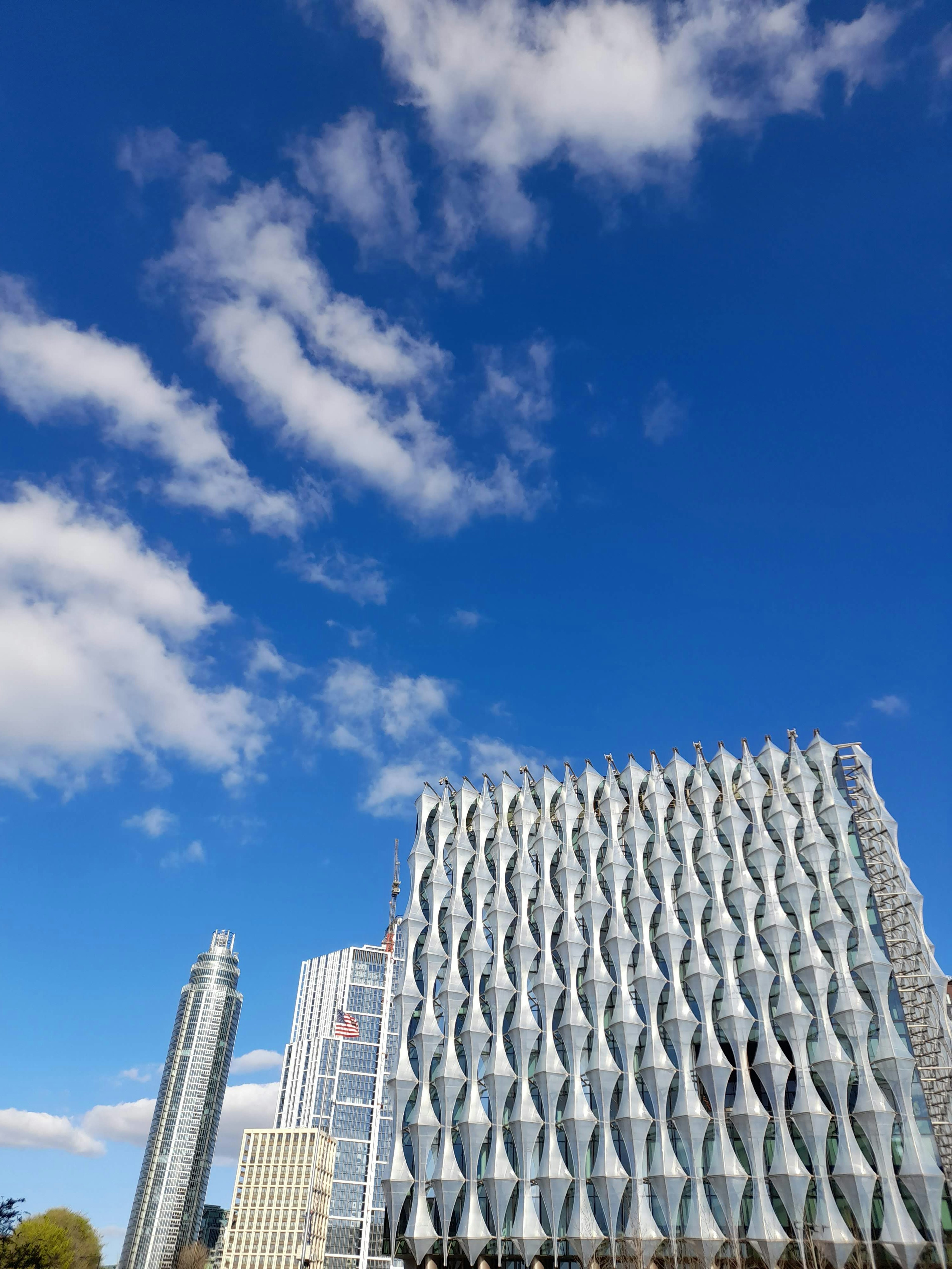 Bâtiment moderne au design ondulé sous un ciel bleu avec des nuages