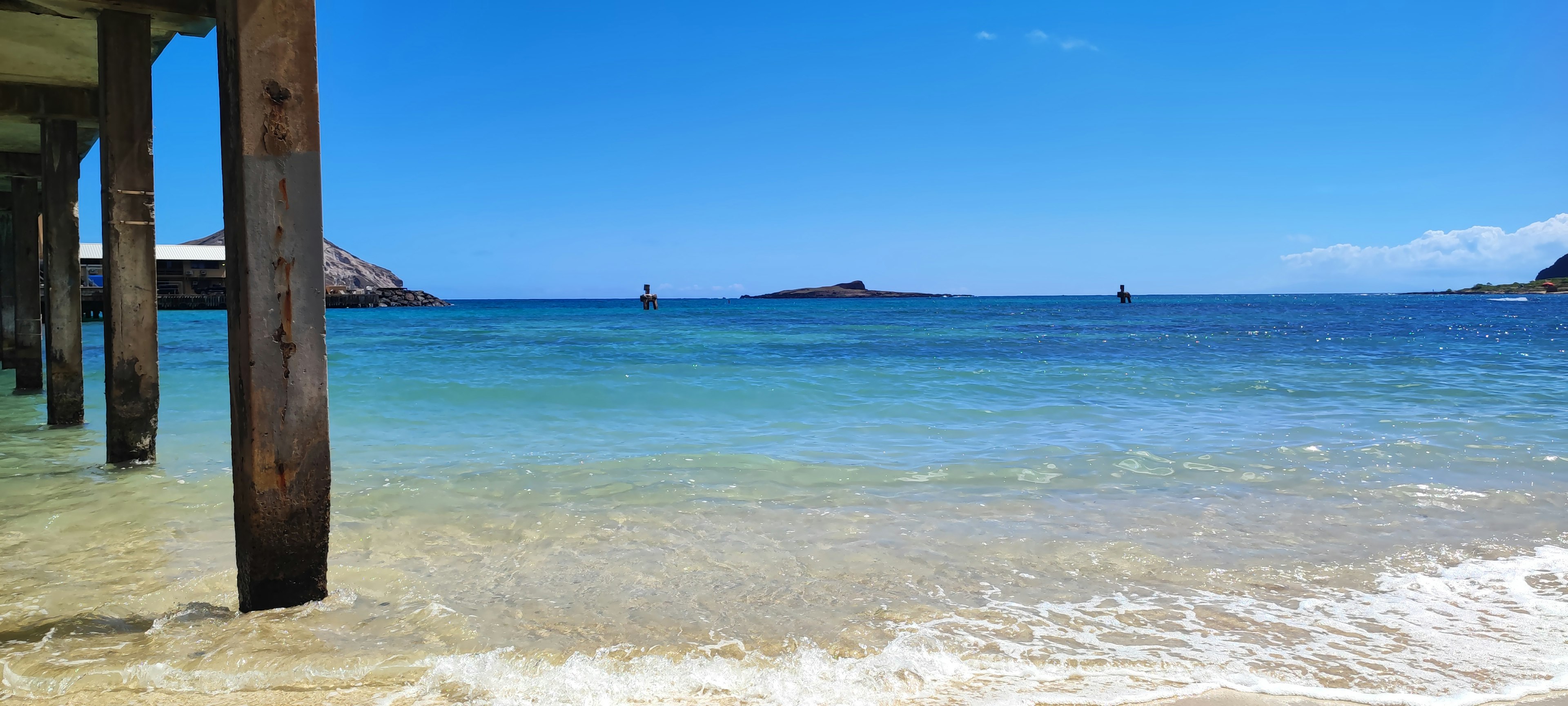 Vue de plage avec mer et ciel bleus piliers de quai visibles