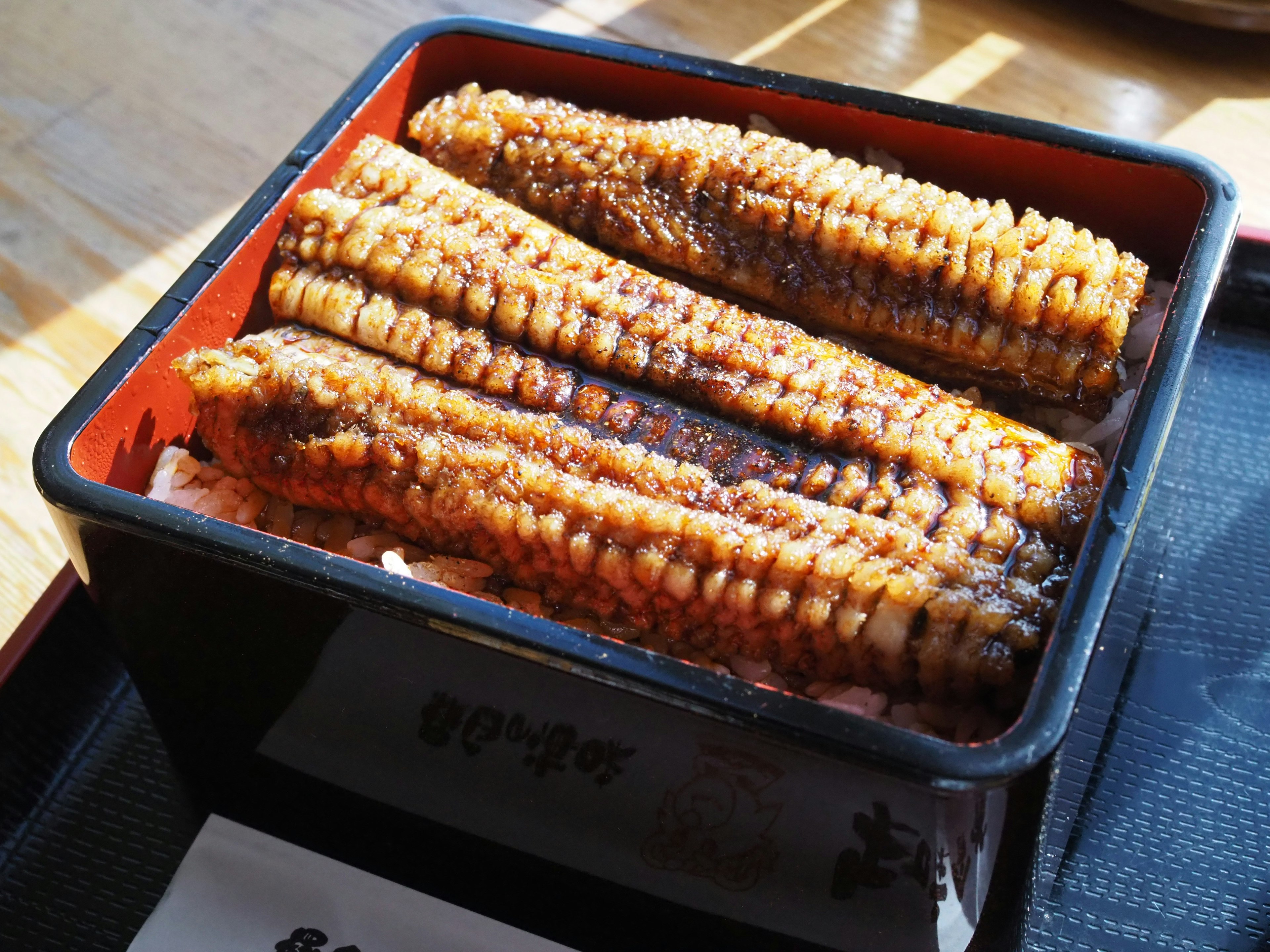 A bento box containing grilled eel with a glossy glaze