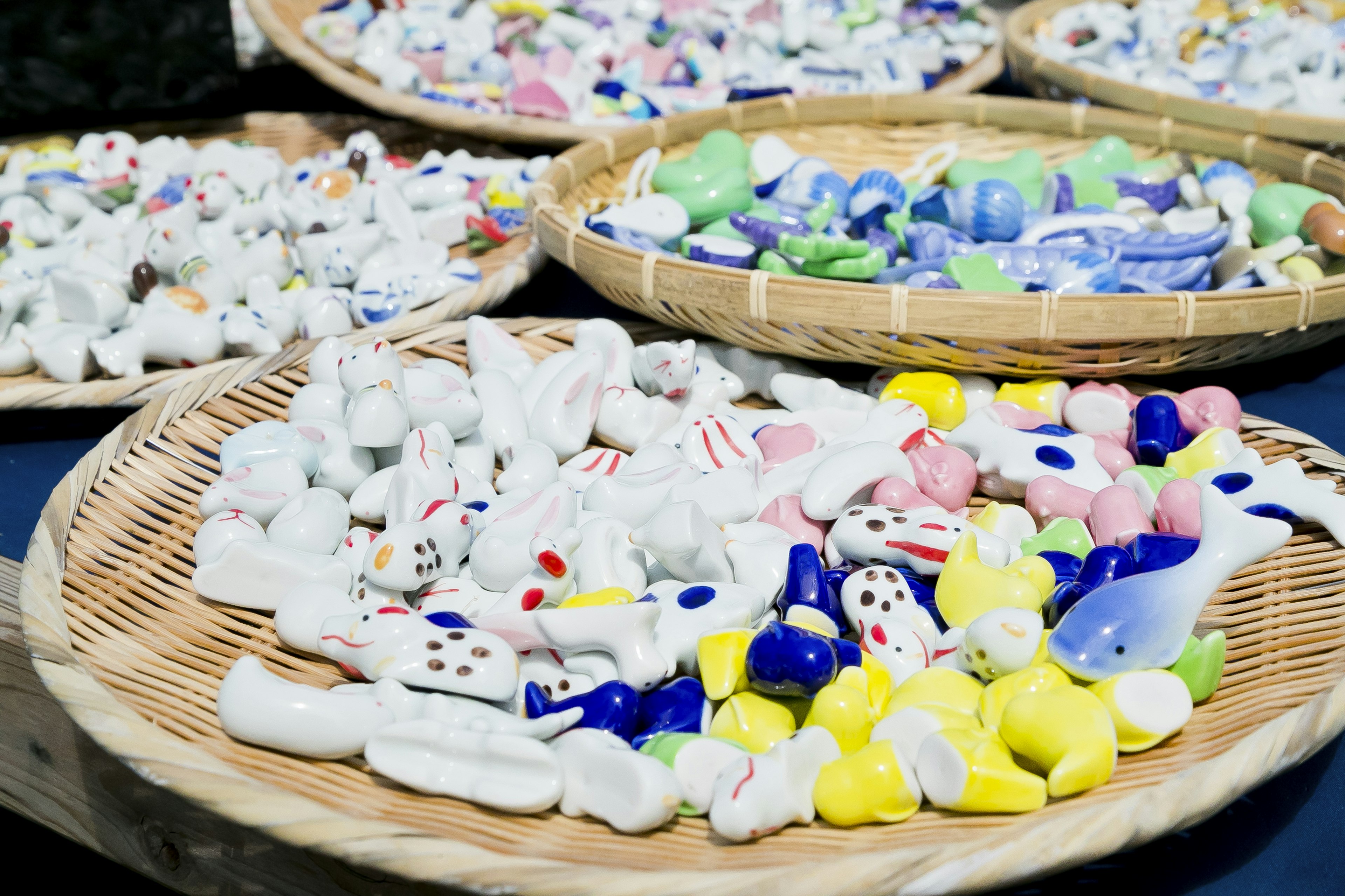 Colorful ceramic figurines arranged on woven bamboo trays