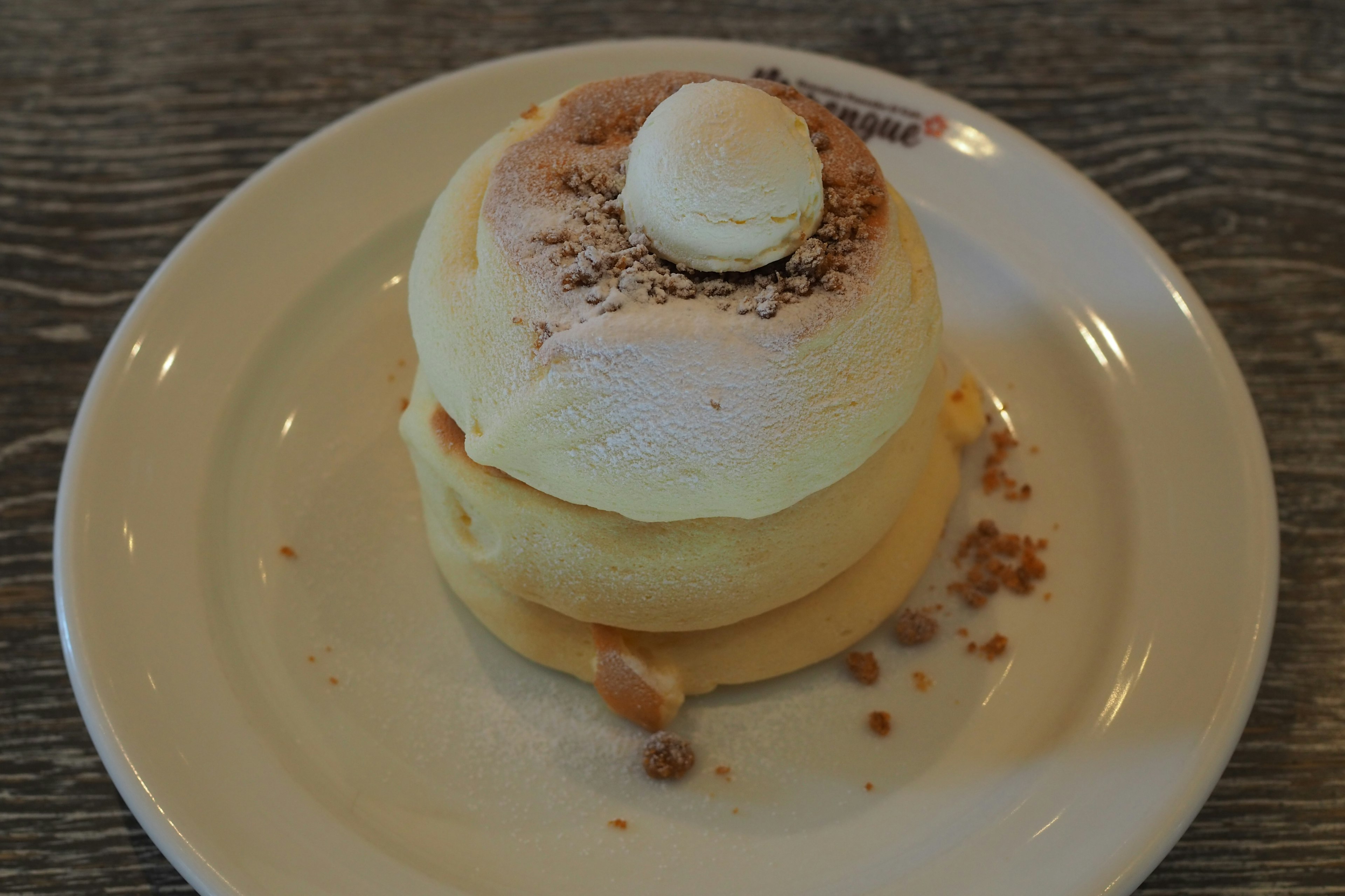 Panqueques esponjosos servidos en un plato con un macarón blanco encima