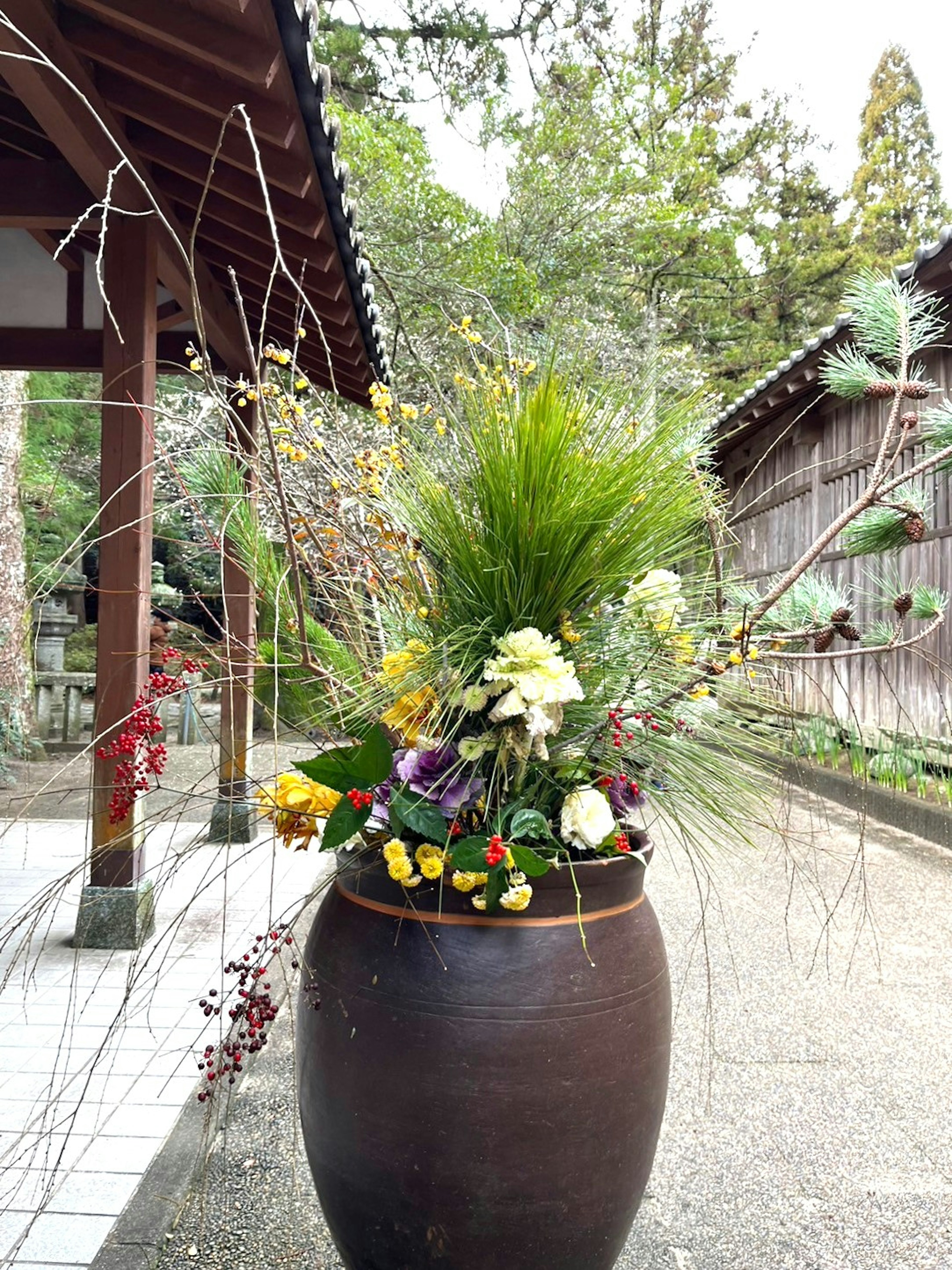 陶器の鉢に生けられた多様な花と緑の植物が特徴的なアレンジメント