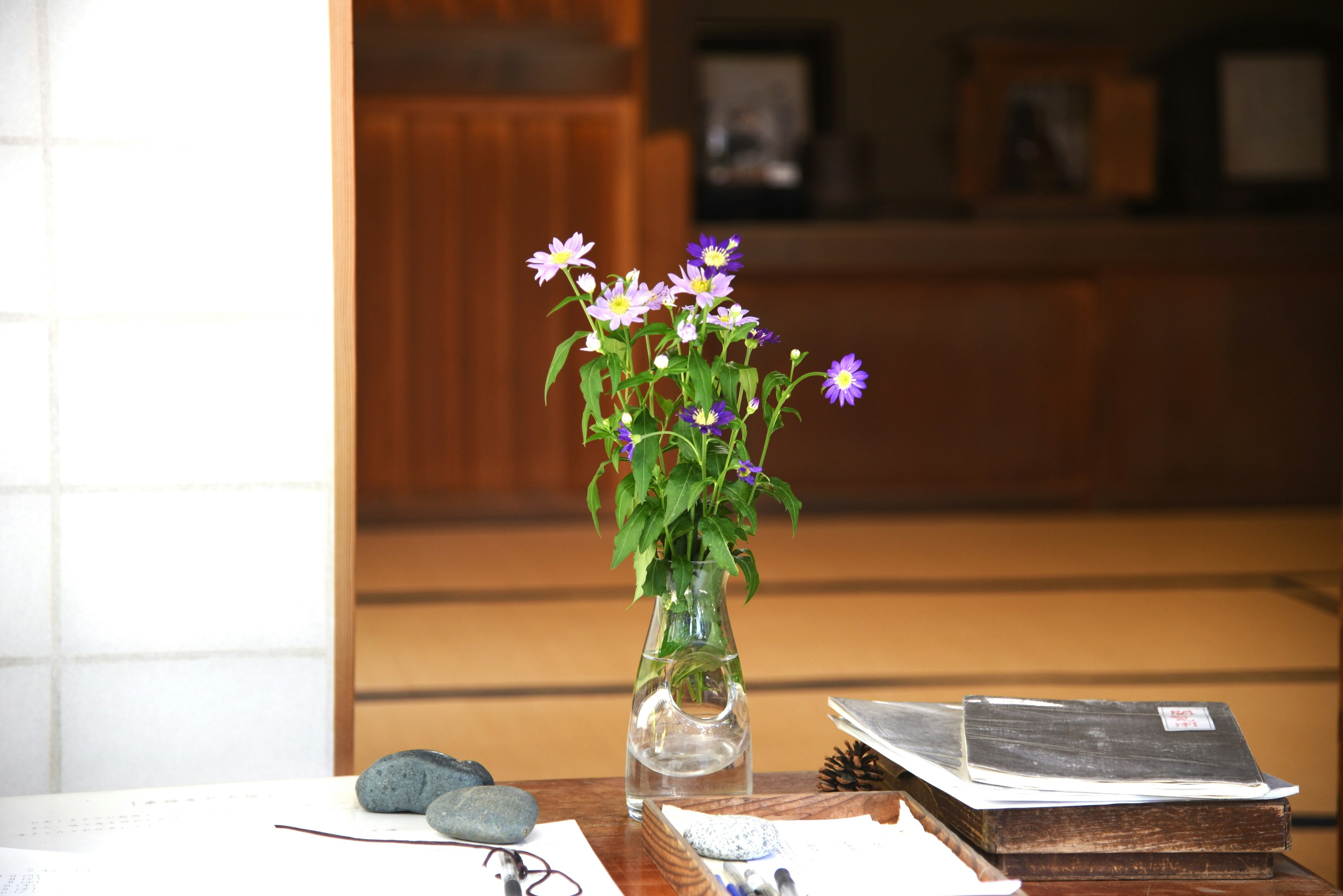 A vase with purple flowers on a table with newspapers