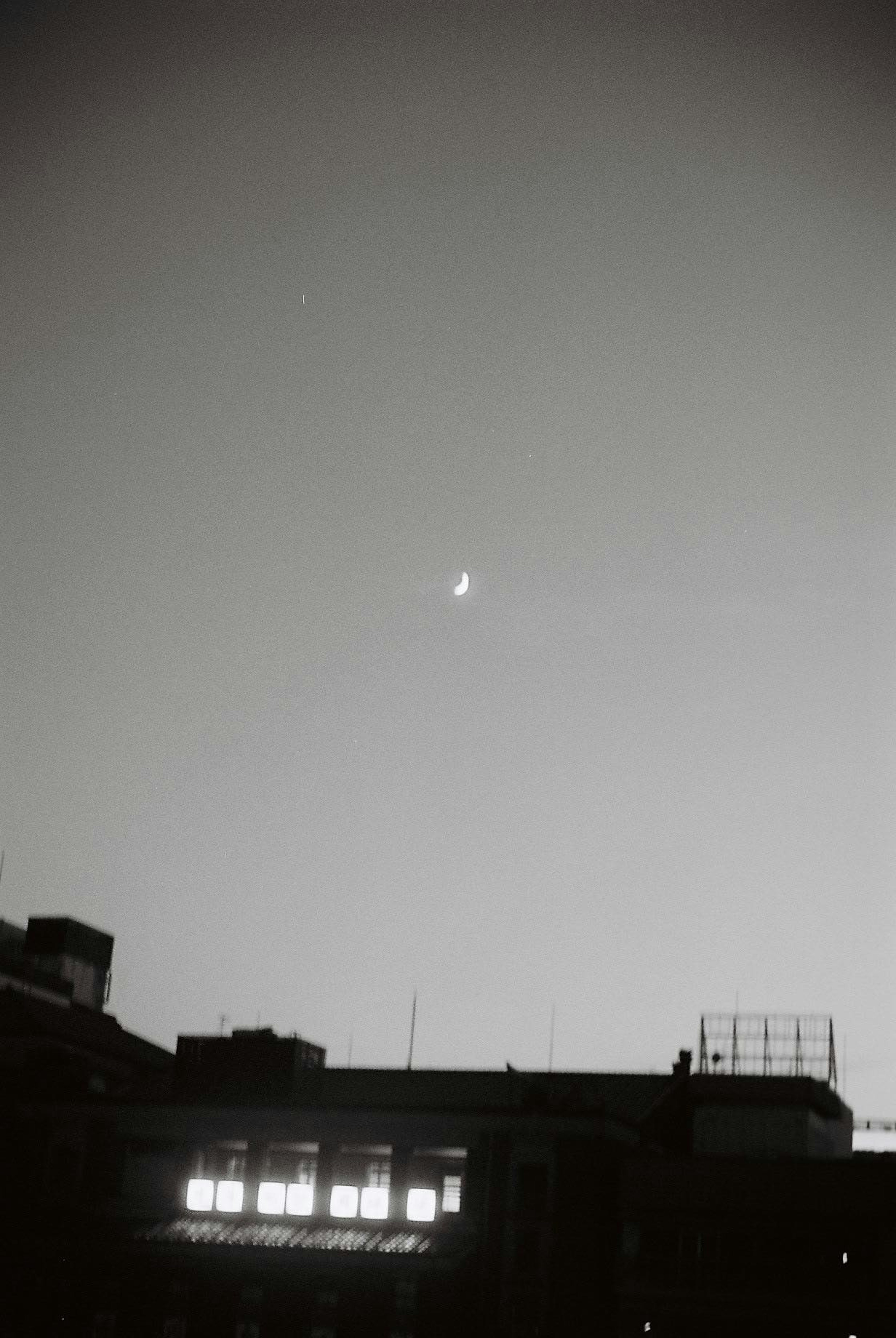 Crescent moon above city skyline at dusk