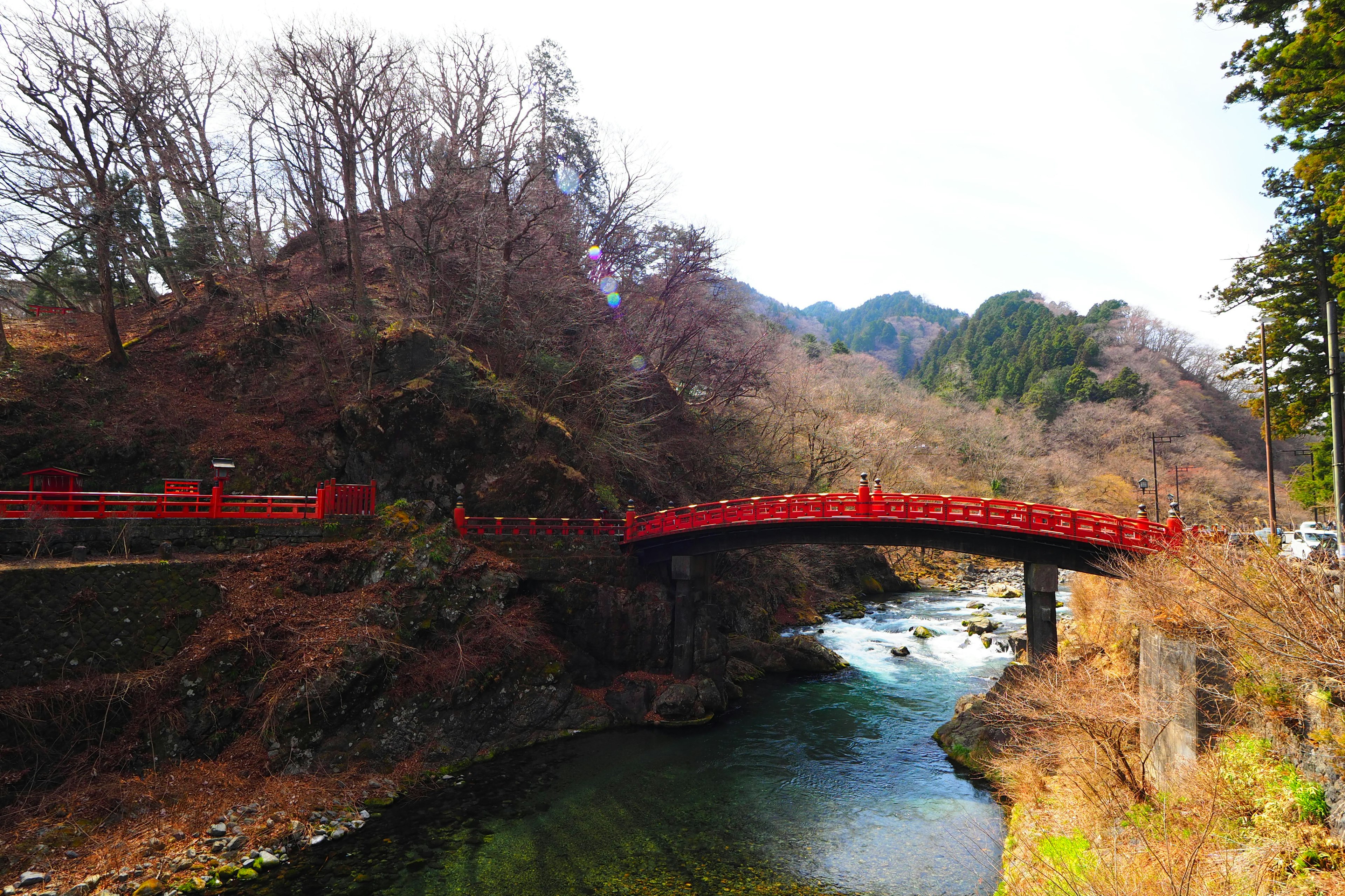 Vista panoramica di un ponte rosso su un fiume calmo con montagne innevate sullo sfondo