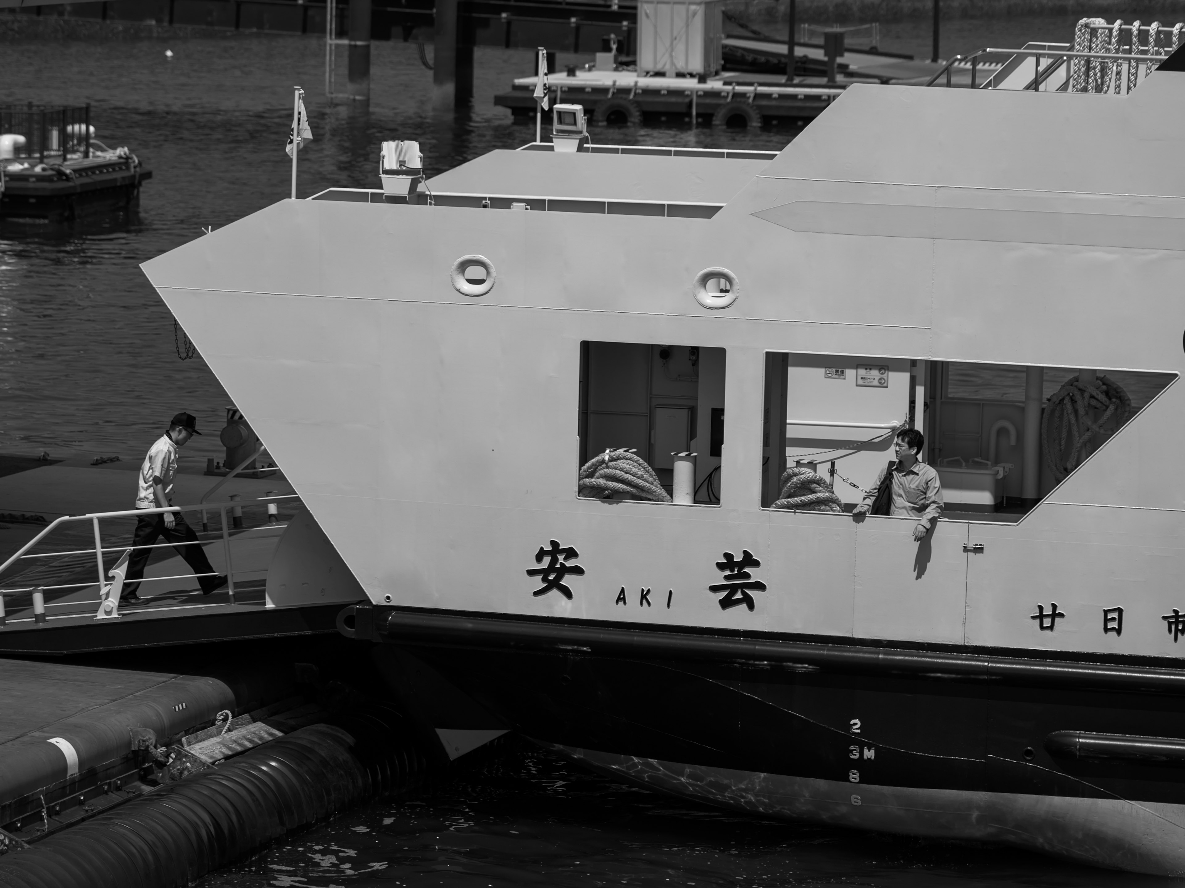 People boarding a ferry with a monochrome harbor backdrop