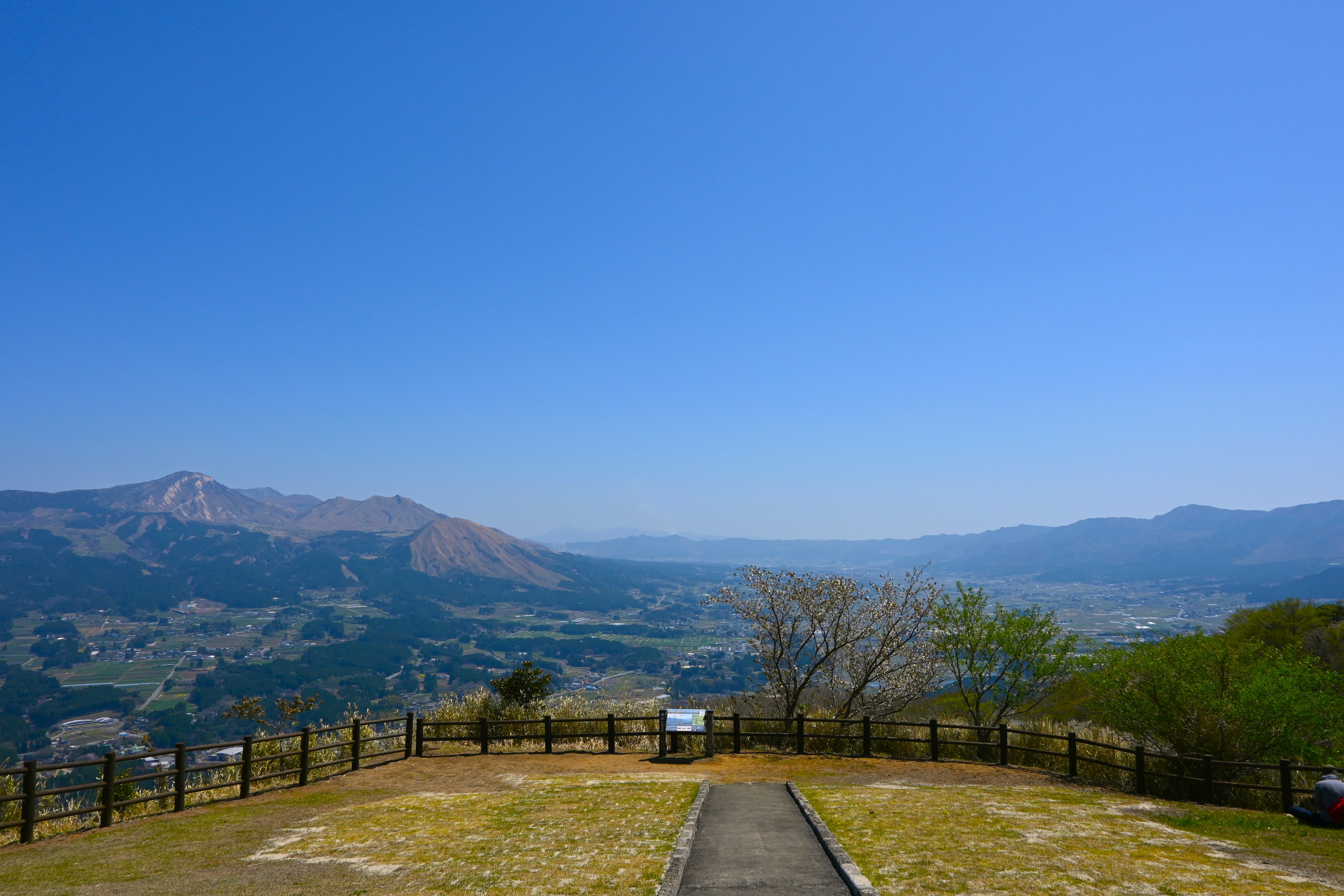 青空の下に広がる山々と谷の景色 道が続く先に見える緑の木々