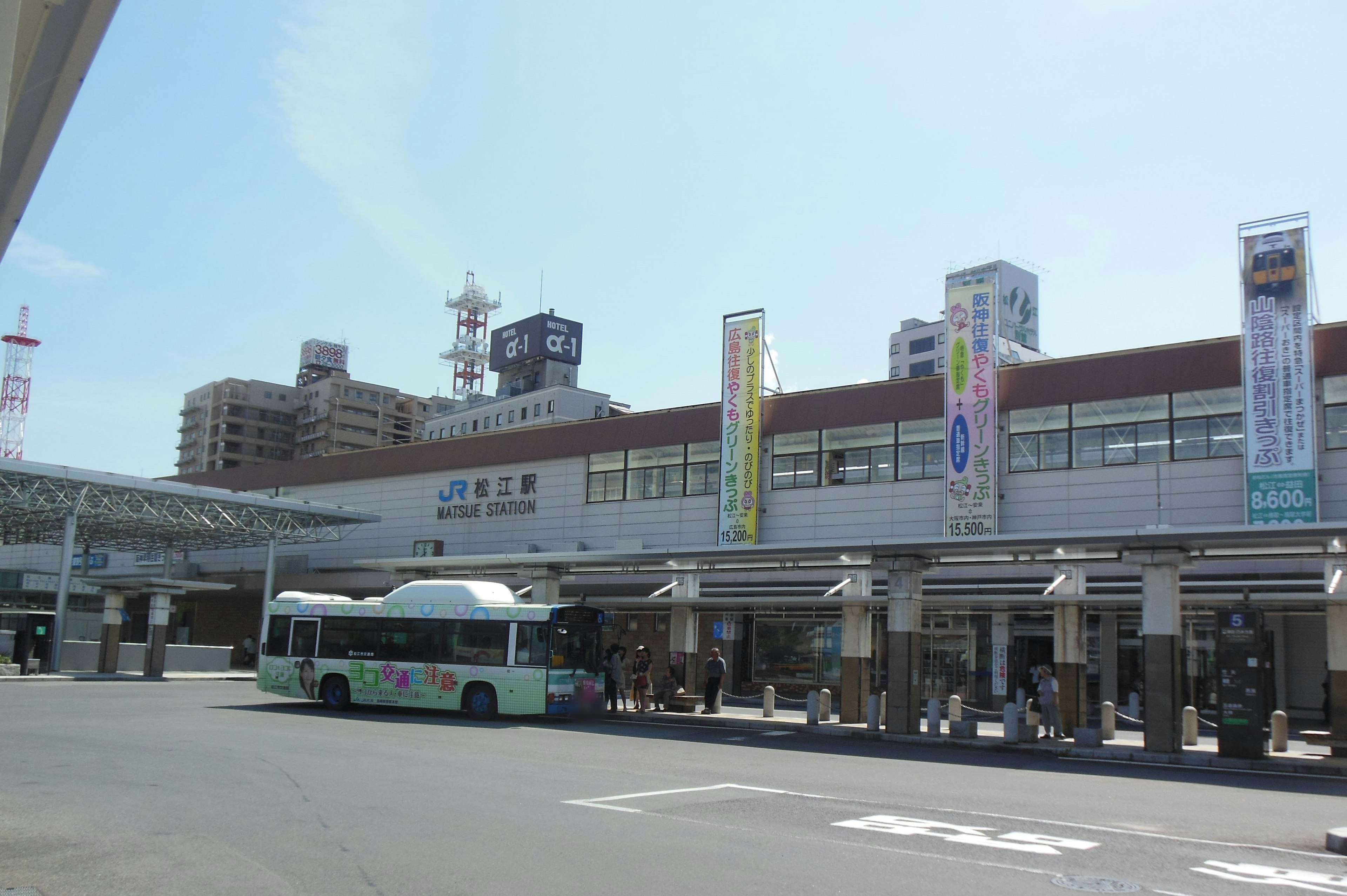 Exterior view of a station with a bus stop under a clear sky