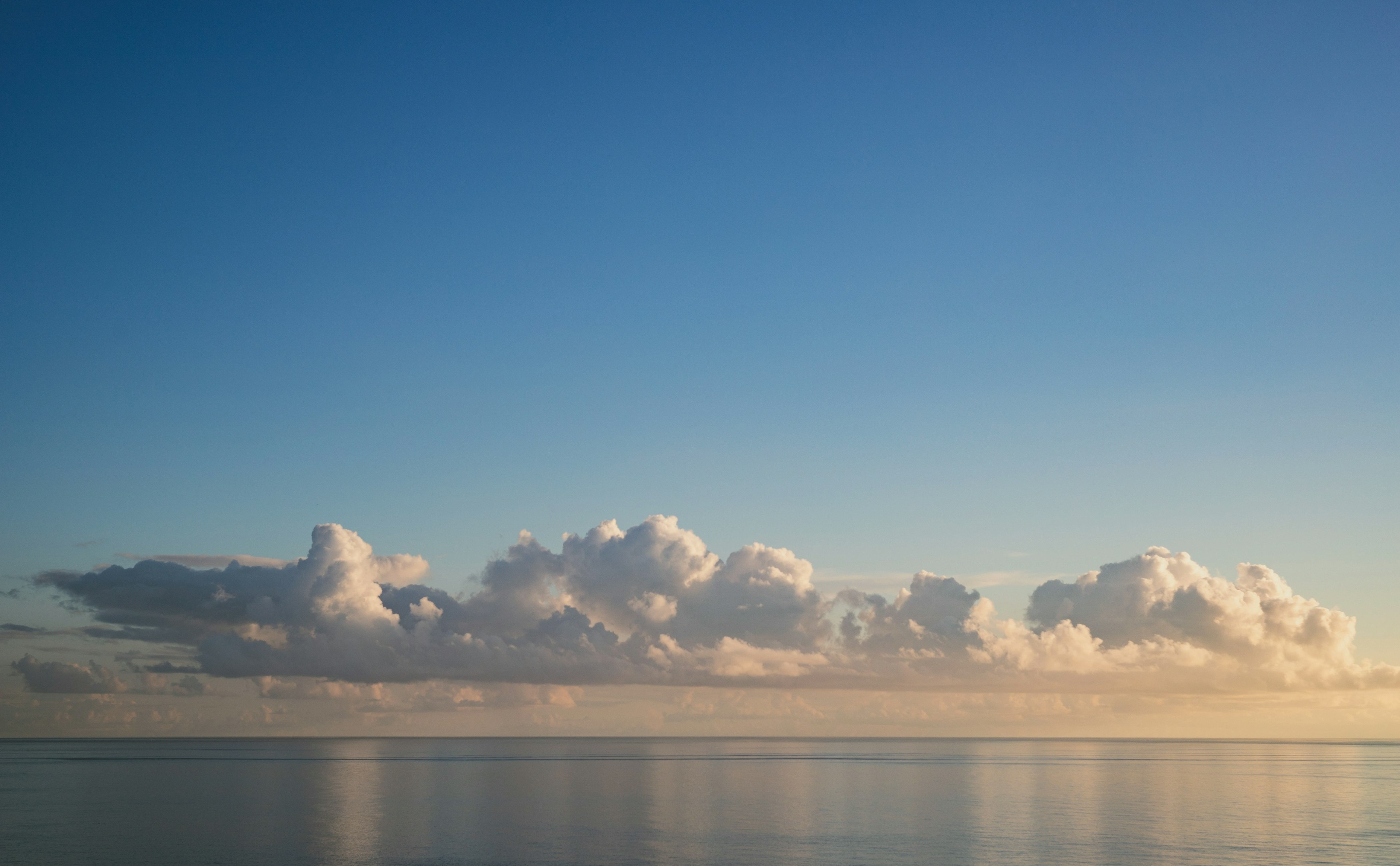 Pemandangan laut tenang dan langit biru dengan awan lembut