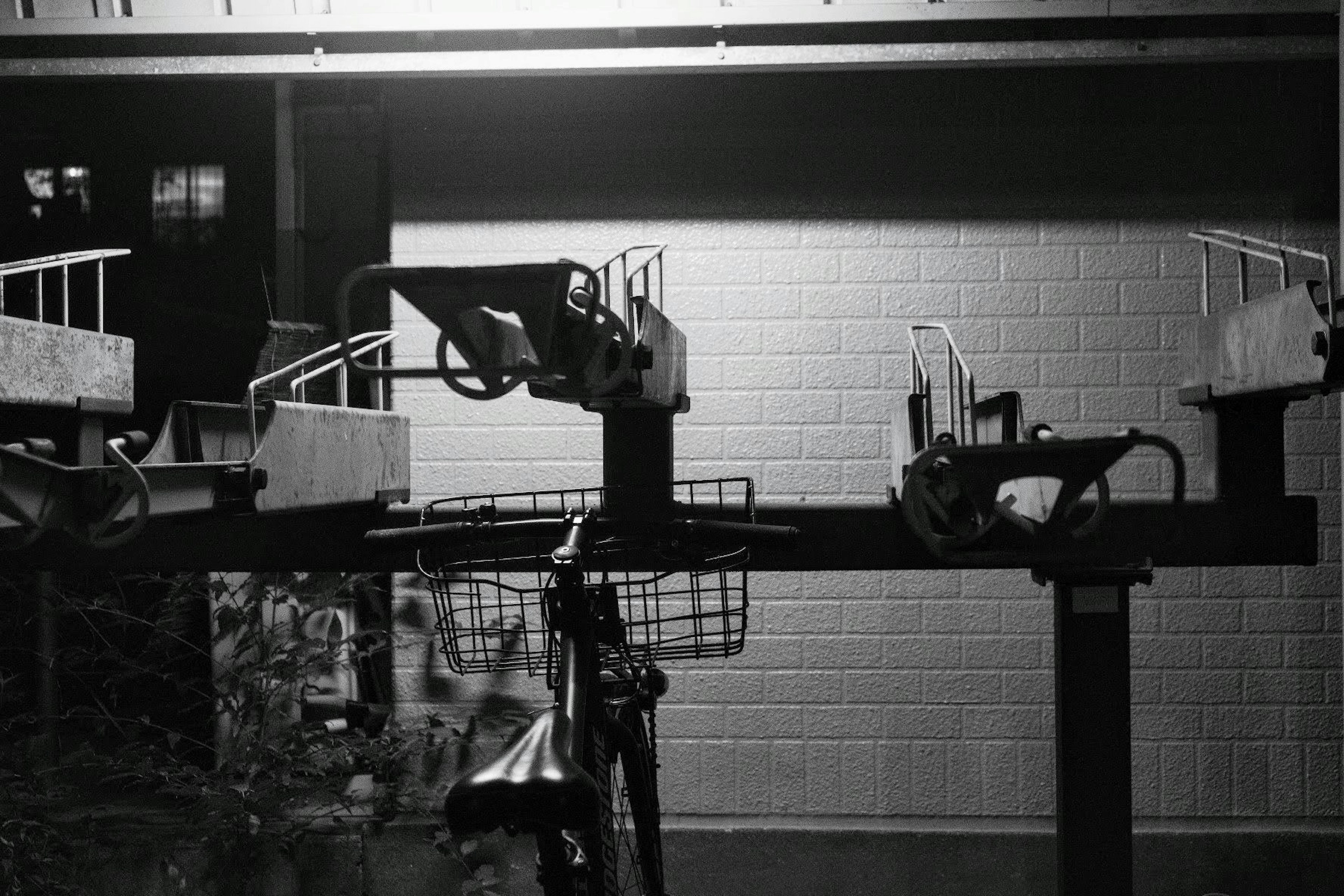 Black and white image featuring a bicycle and surrounding structures at night