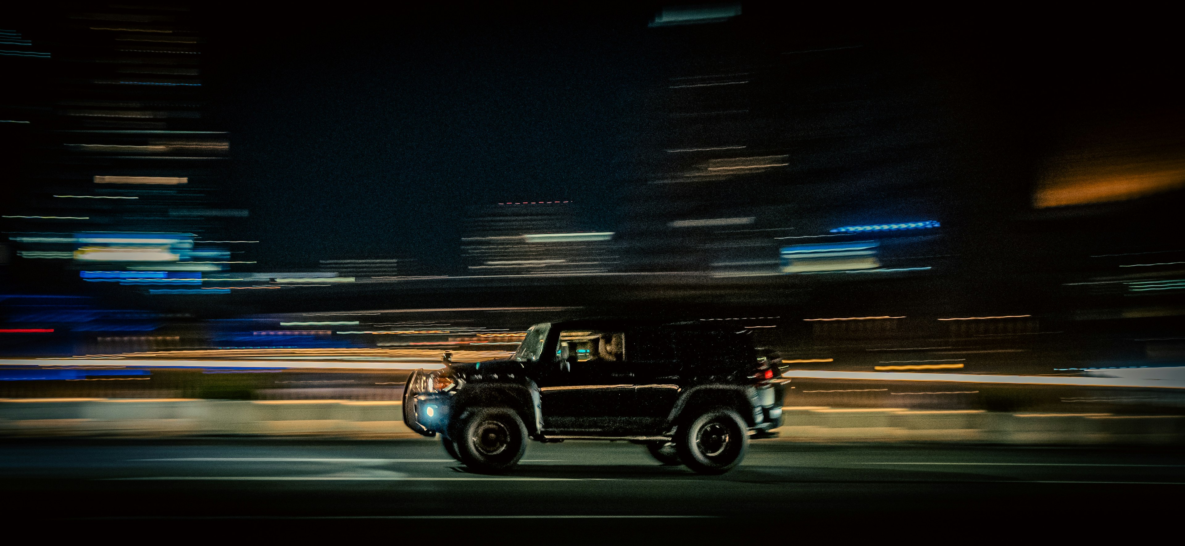 A dynamic shot of a black SUV speeding through a city at night