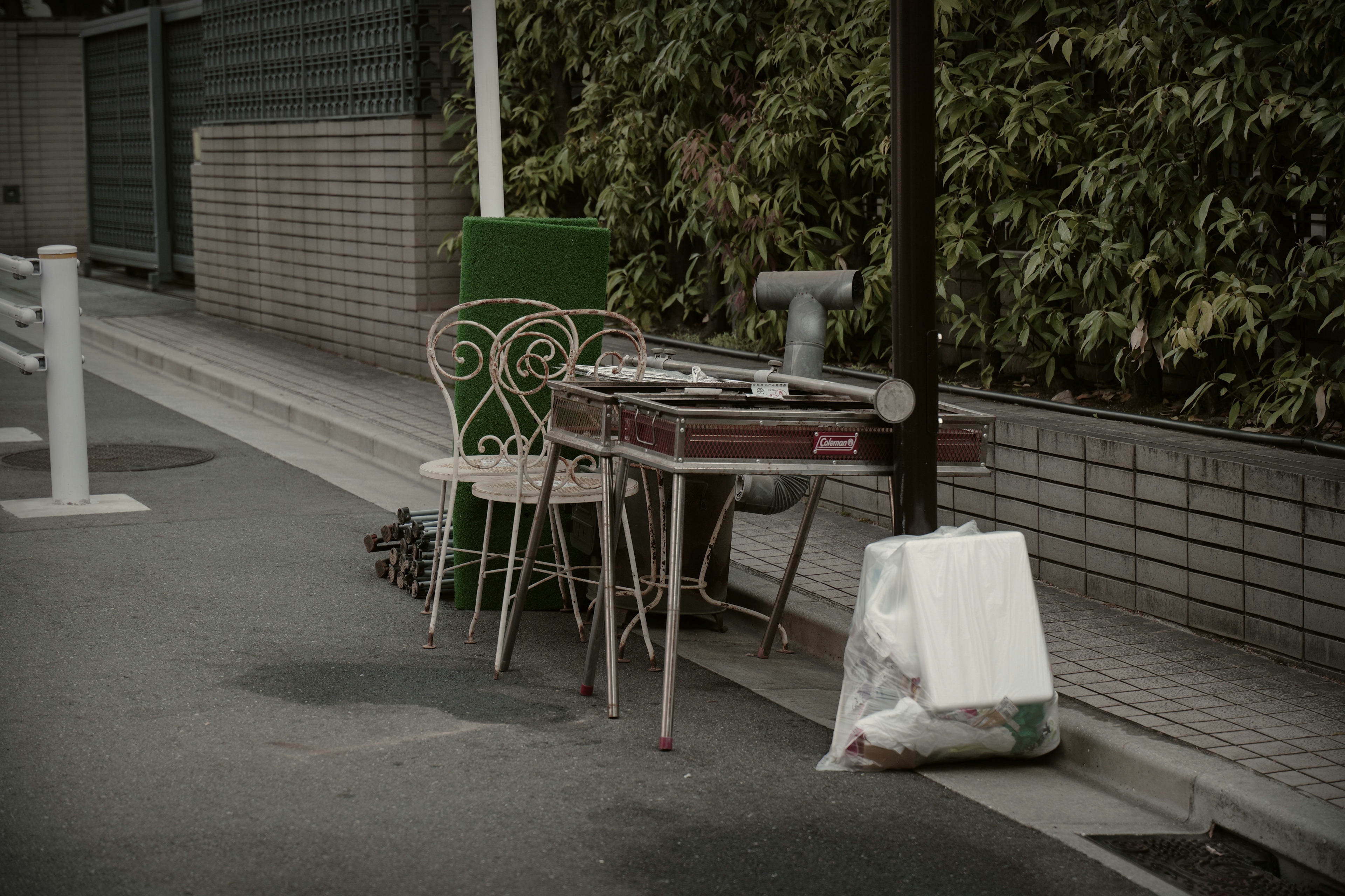Un vieux set de table et de chaises placé dans la rue avec un sac poubelle