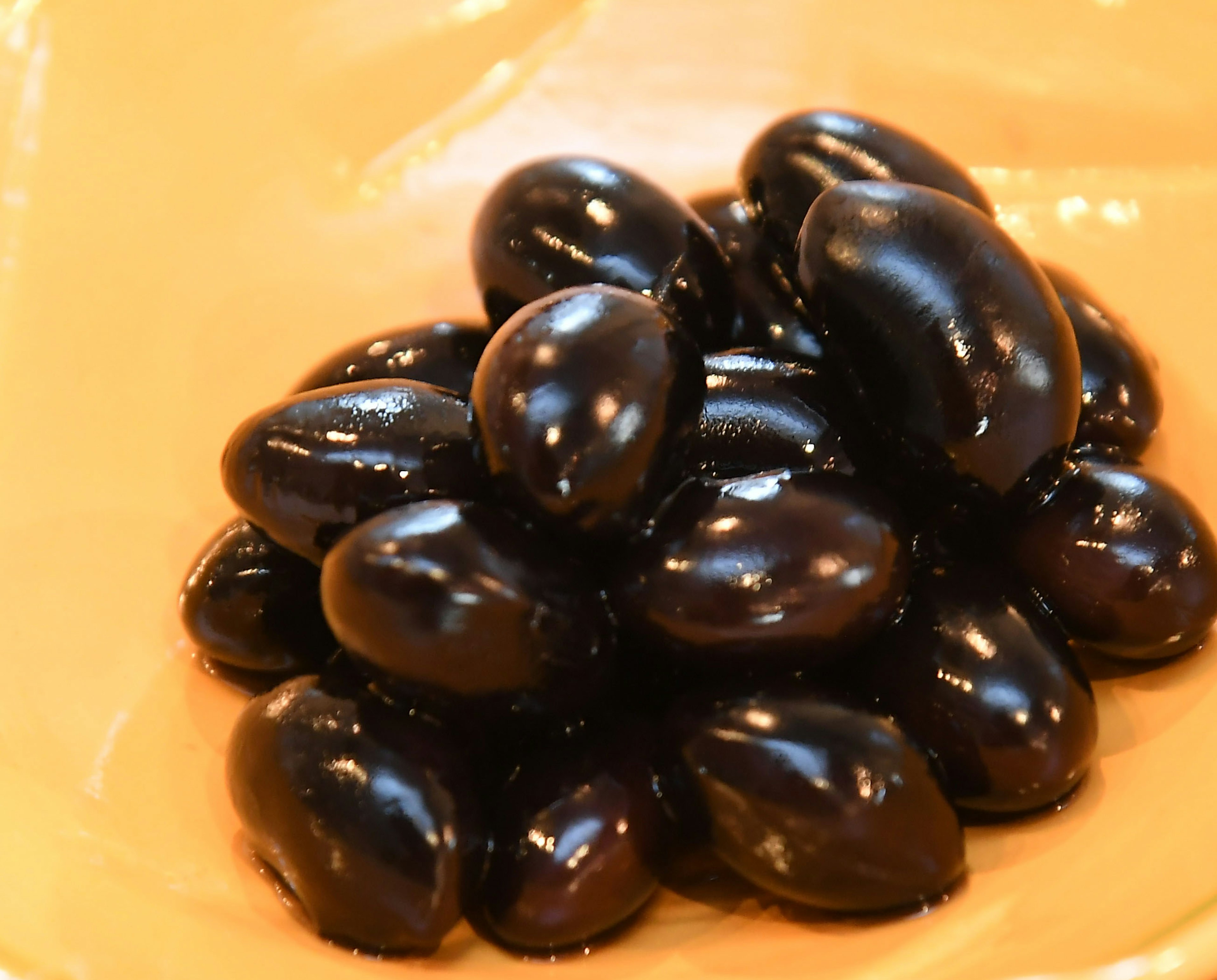 A pile of shiny black beans on a light-colored plate