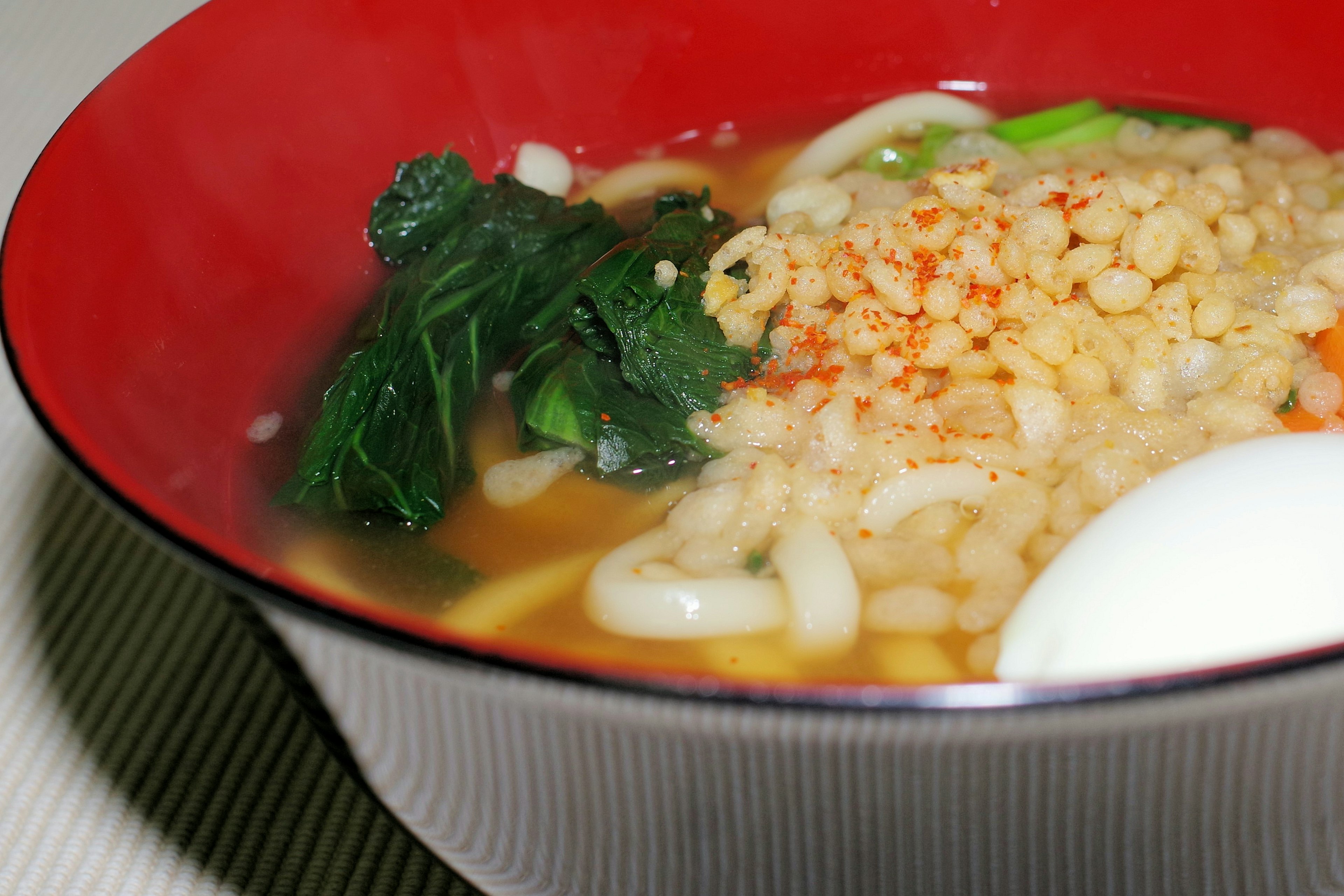 Udon noodles and spinach soup in a red bowl