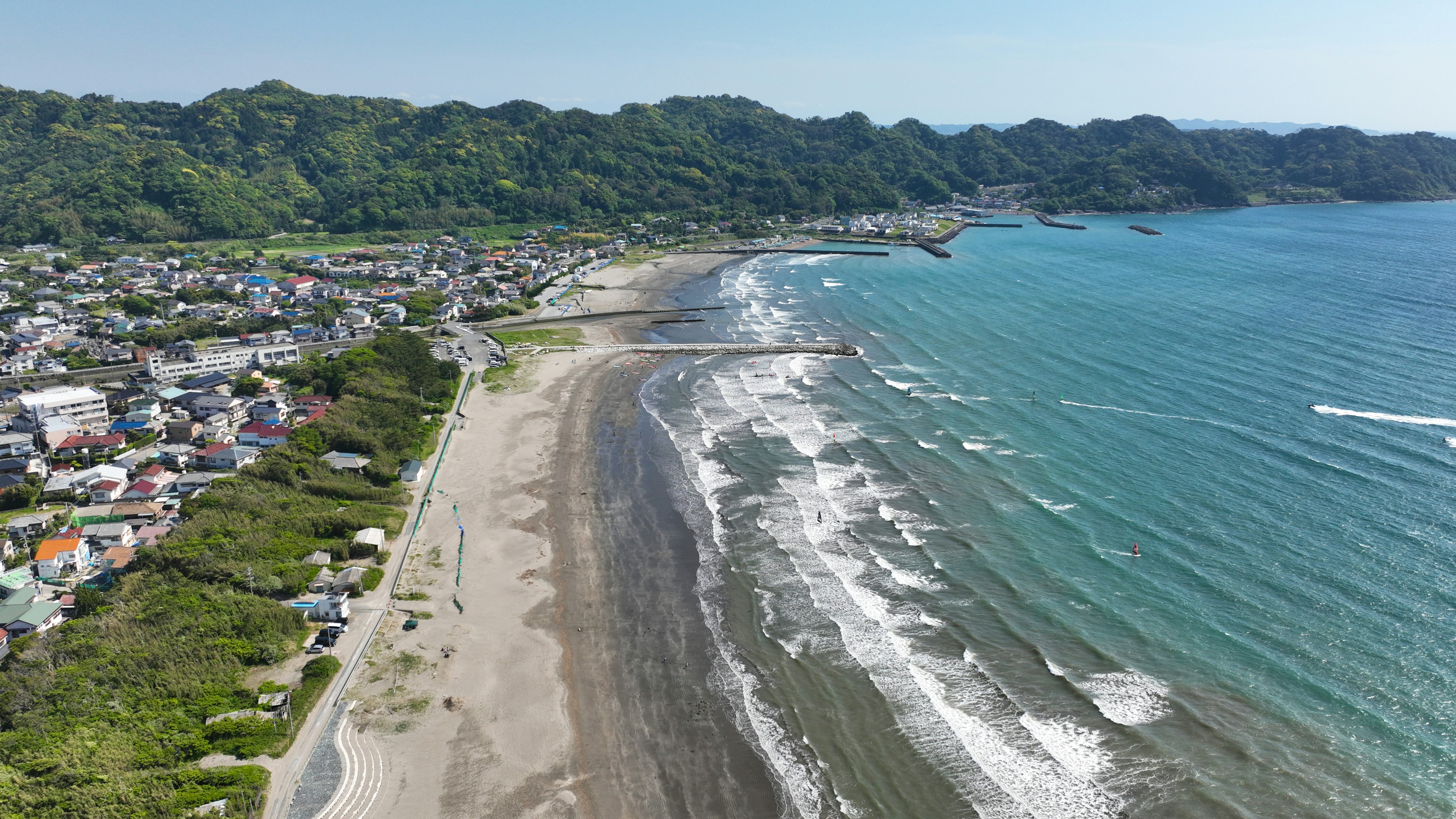 Aerial view of a coastline and town featuring green hills and blue sea