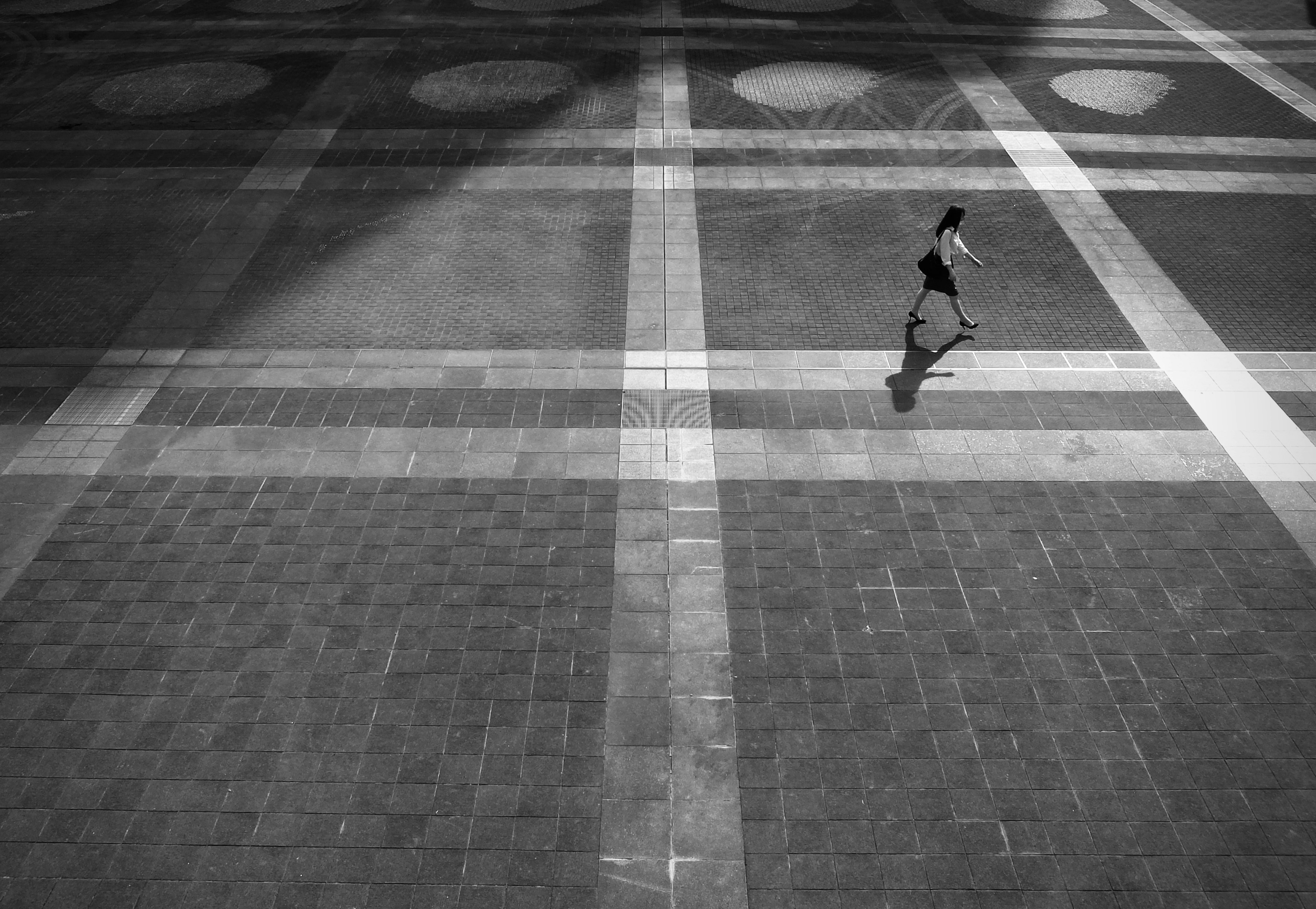 Silhouette seseorang berjalan di plaza berpola hitam dan putih