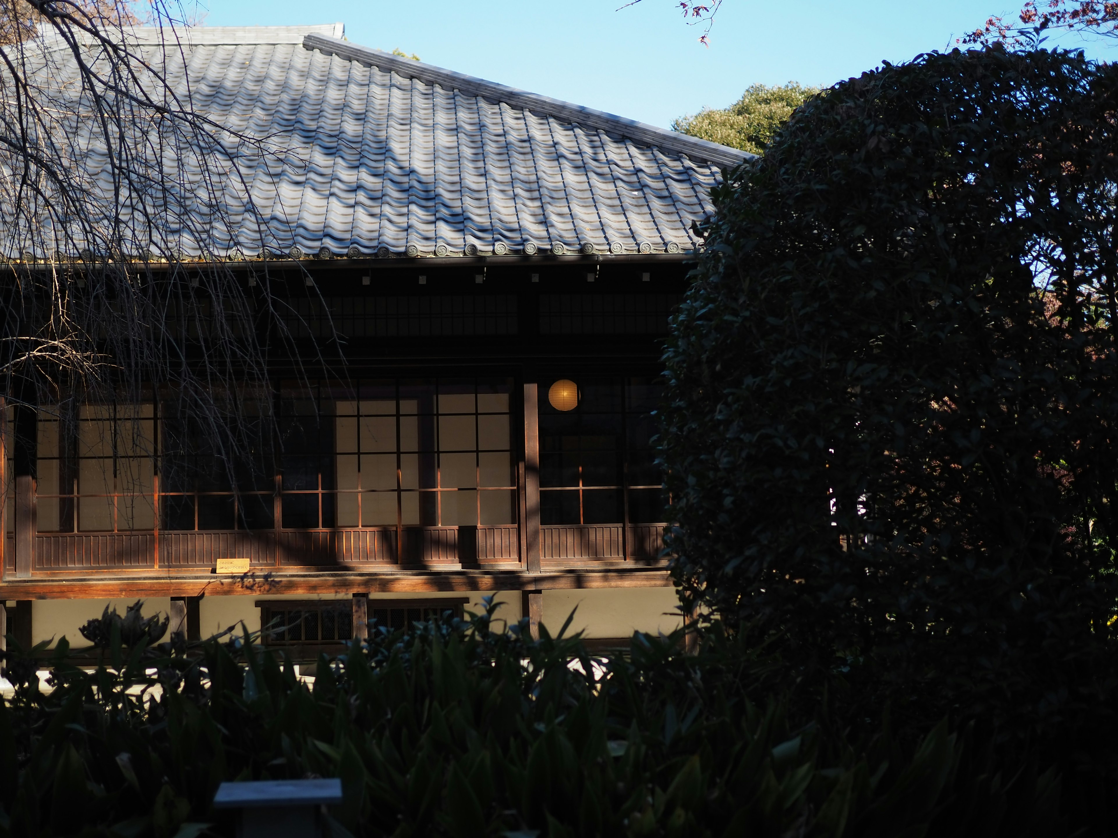 Casa japonesa tradicional con techo de tejas y vista al jardín