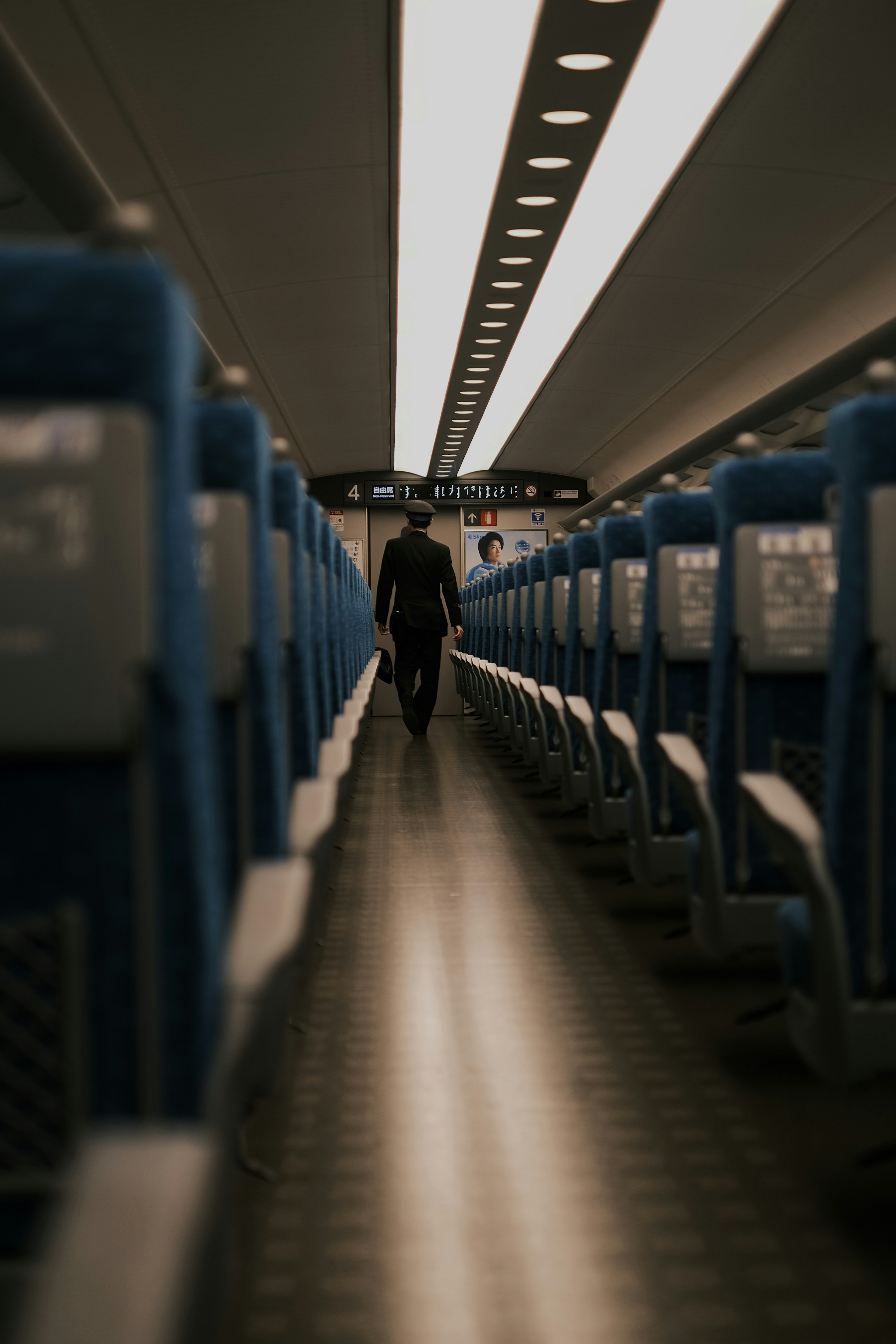 空いている電車の車両の通路を歩く人