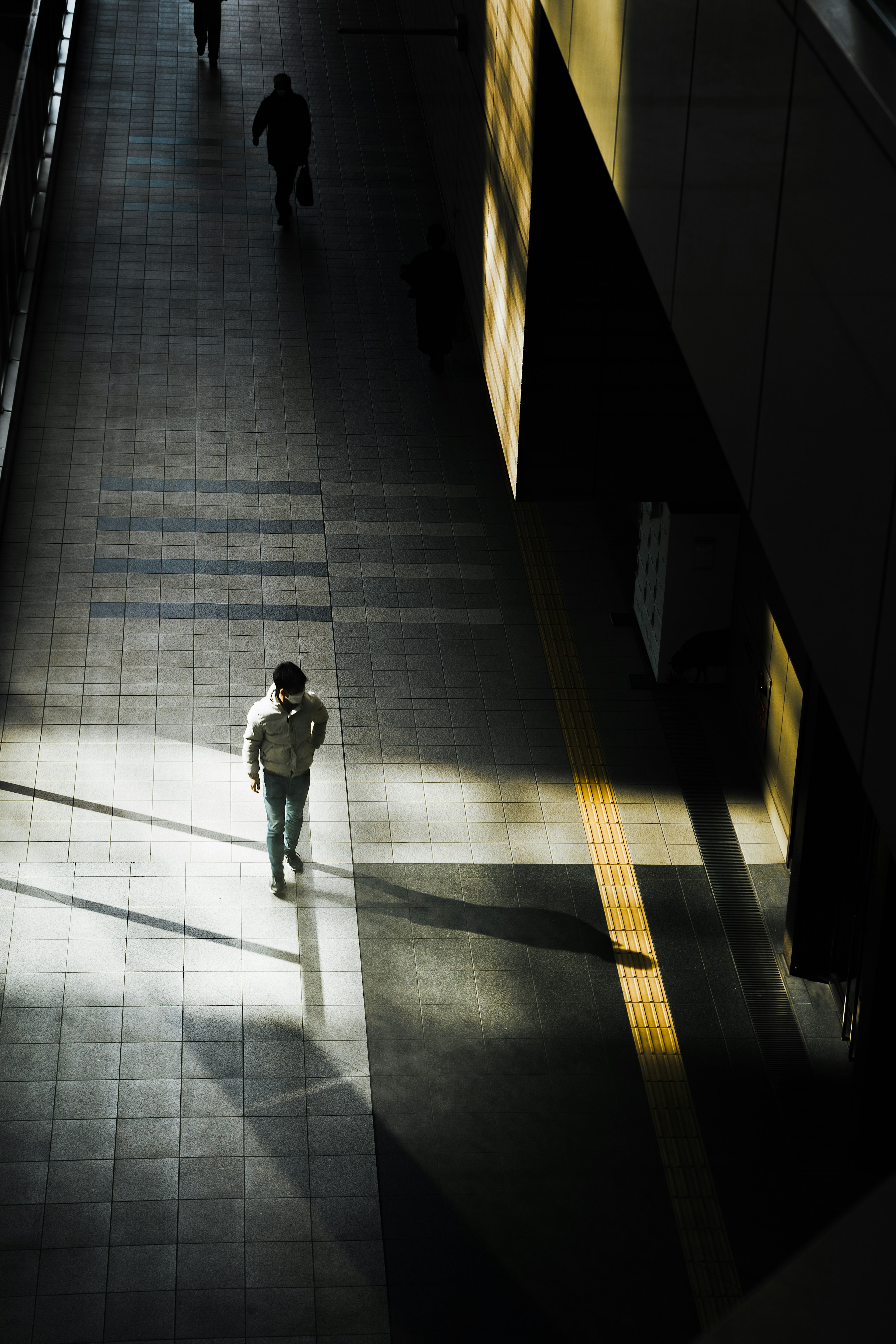 Una silueta caminando en un pasillo tenue con luz contrastante