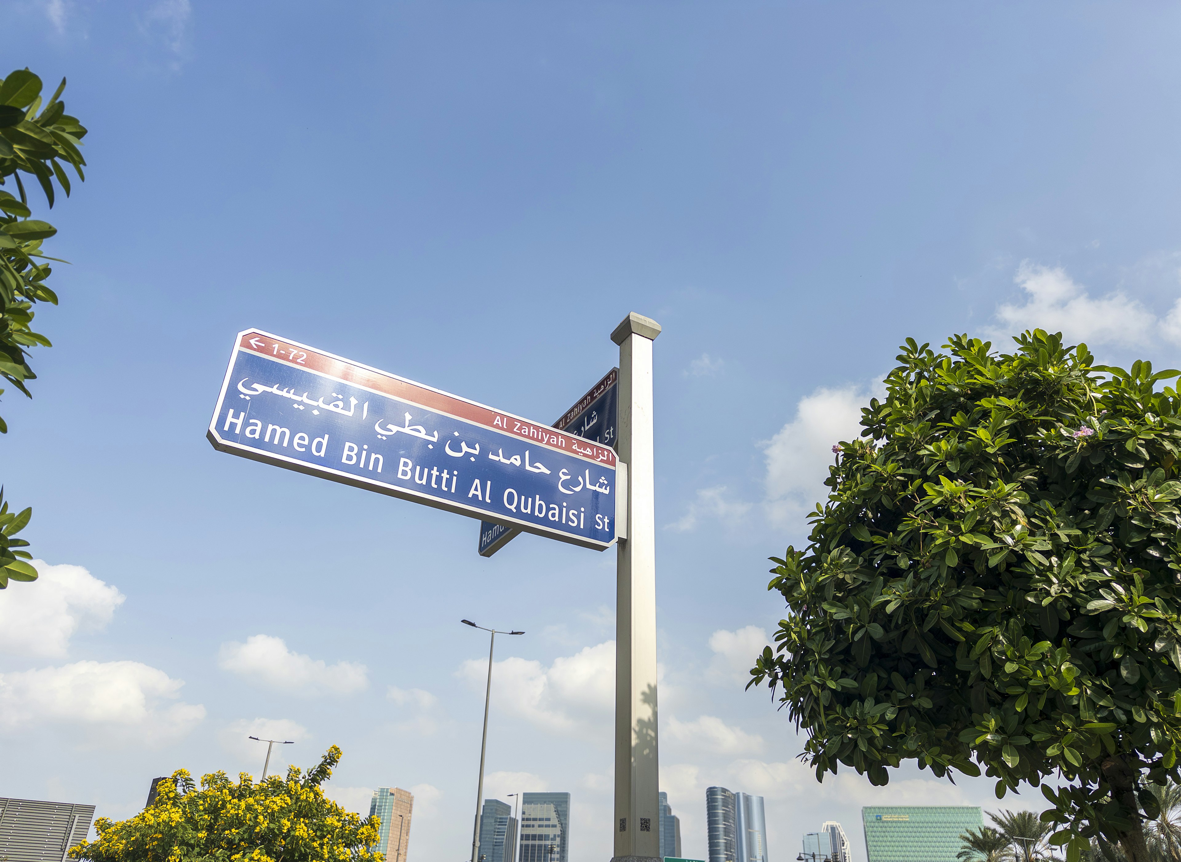 Road sign under blue sky displaying Hamad bin Butti Al Qatami