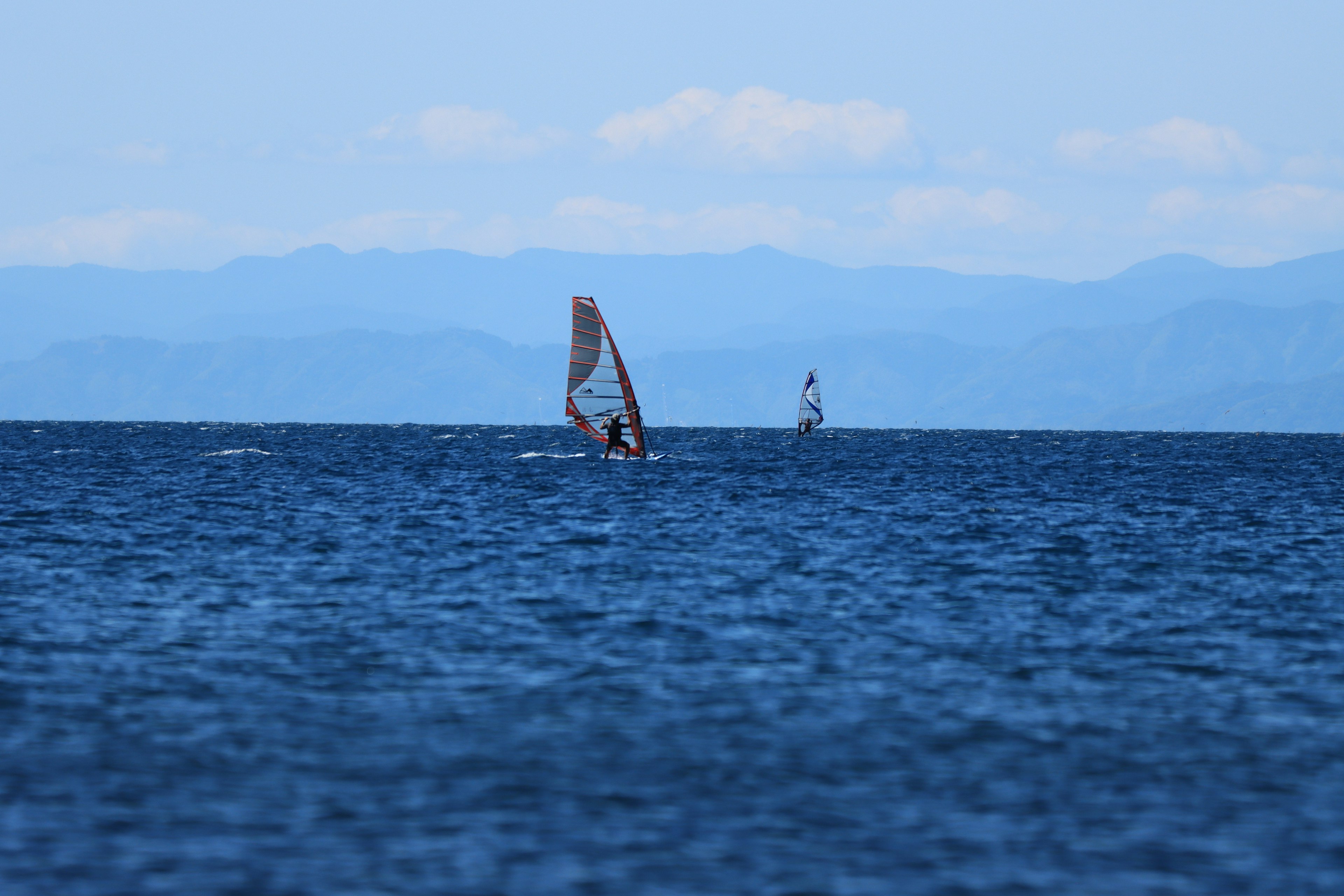 Perahu layar di lautan biru dengan gunung jauh