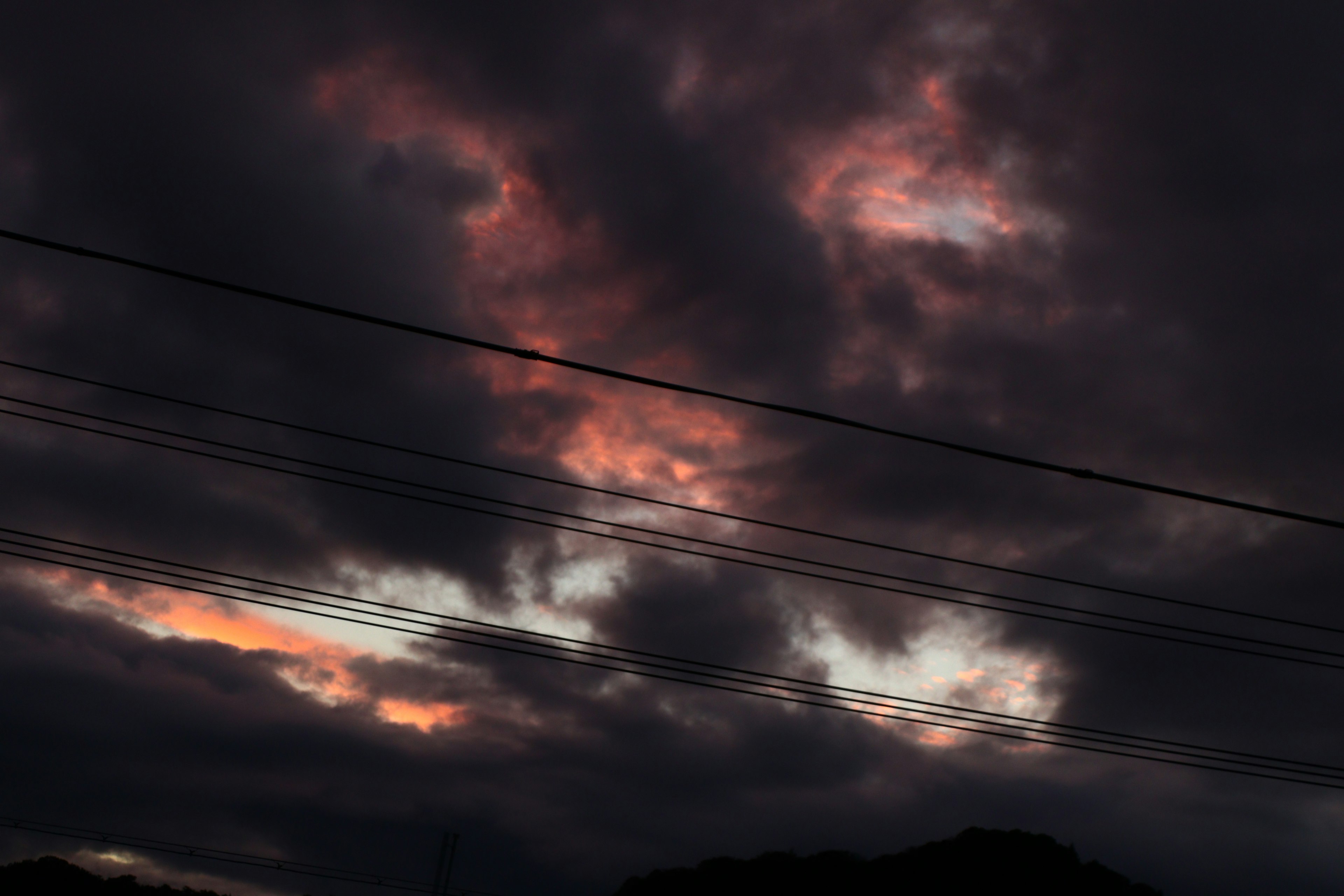 Cielo drammatico con nuvole scure e tonalità vibranti di arancione e rosa al tramonto