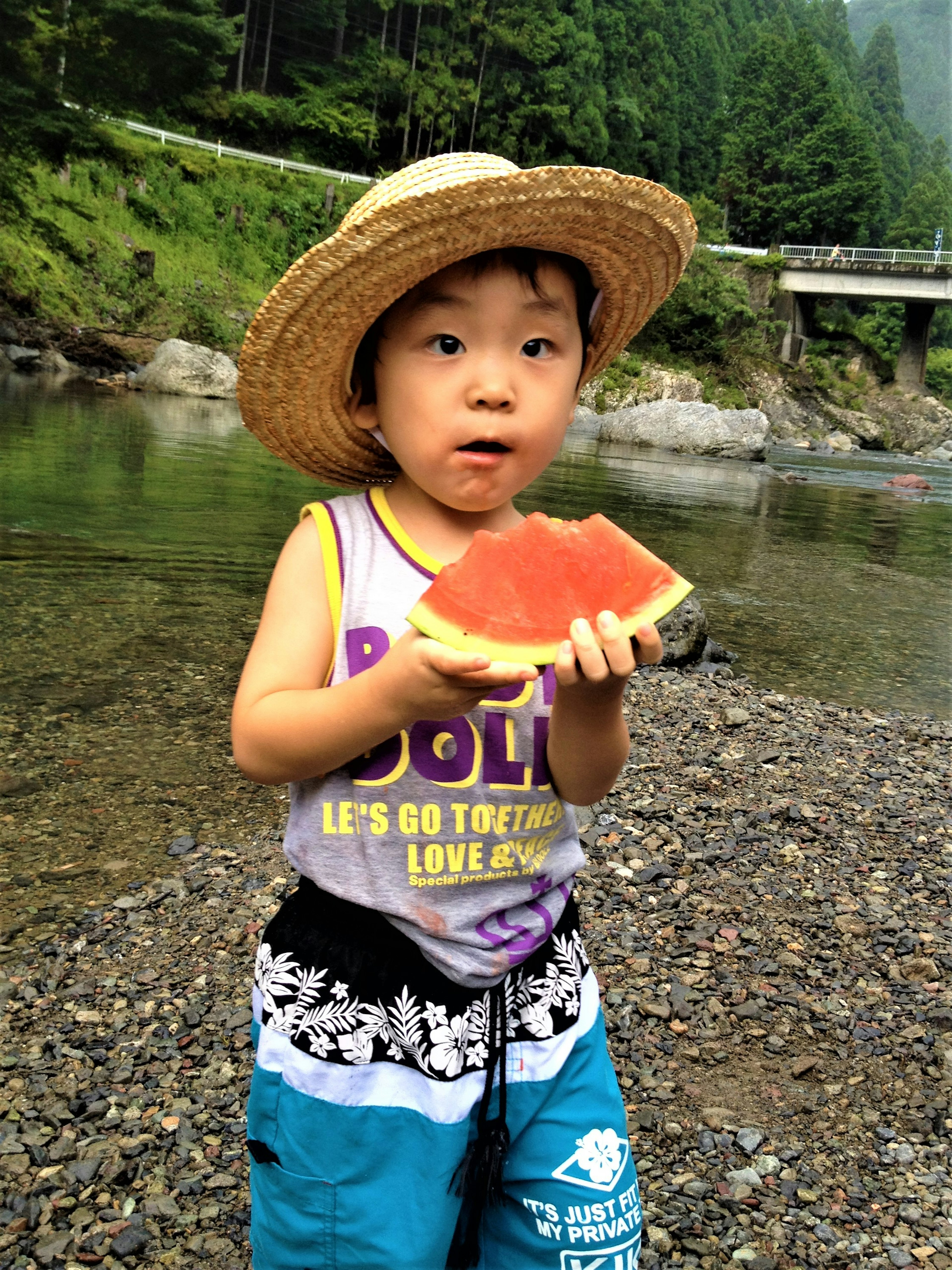 水辺でスイカを持つ子供の写真