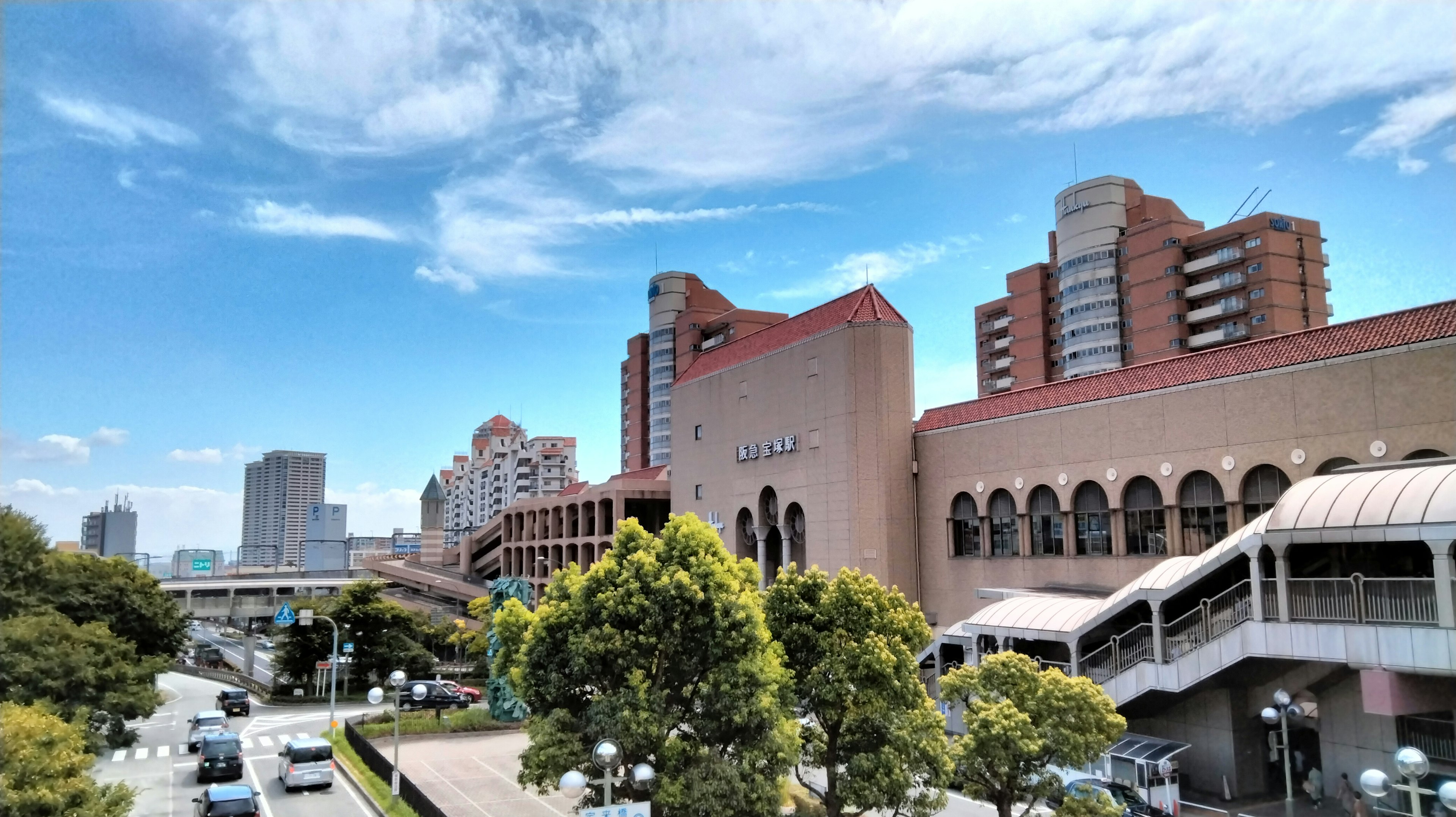 Urban landscape featuring modern buildings and green trees under a blue sky