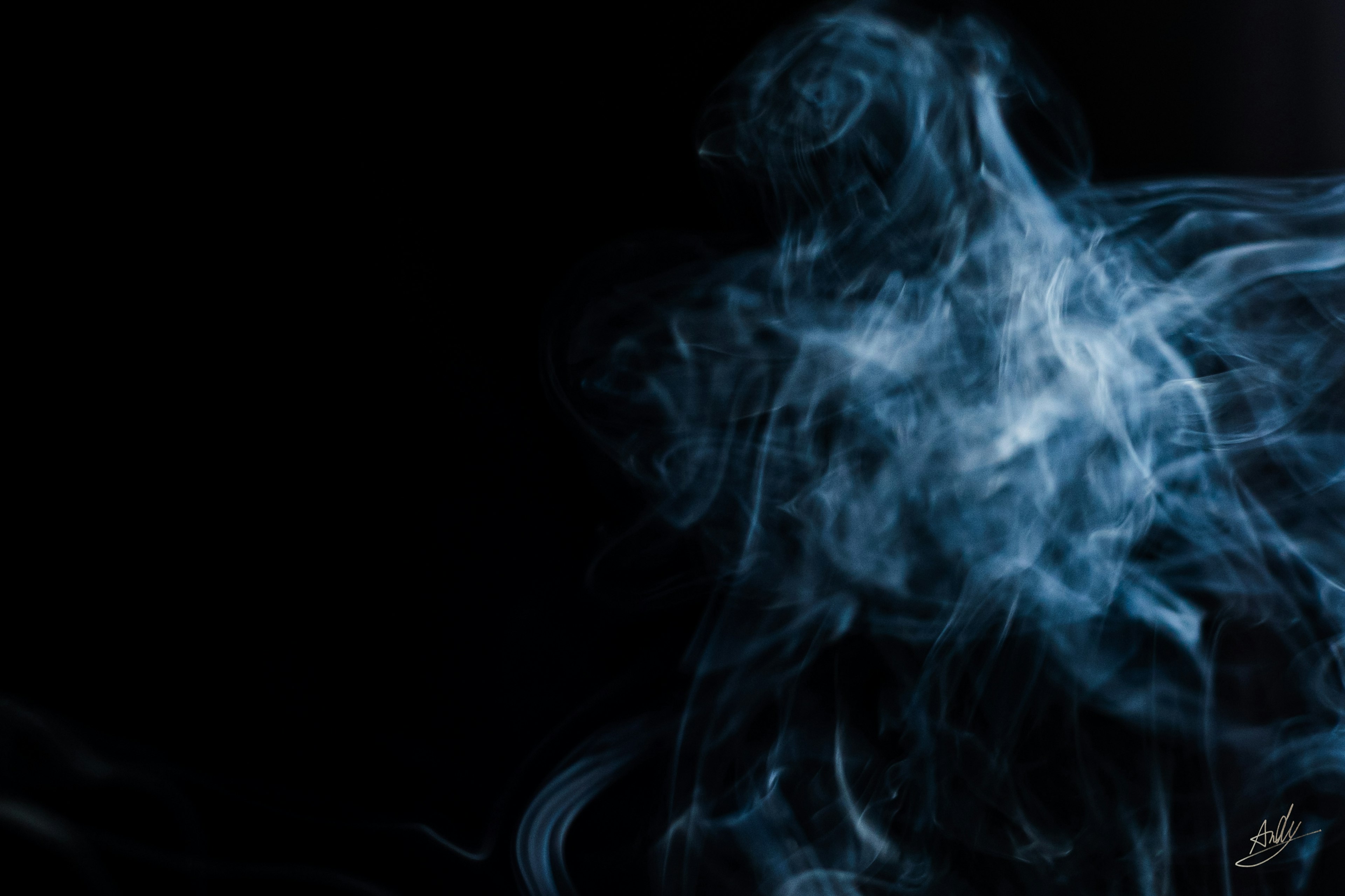 A mystical image of blue smoke swirling against a black background