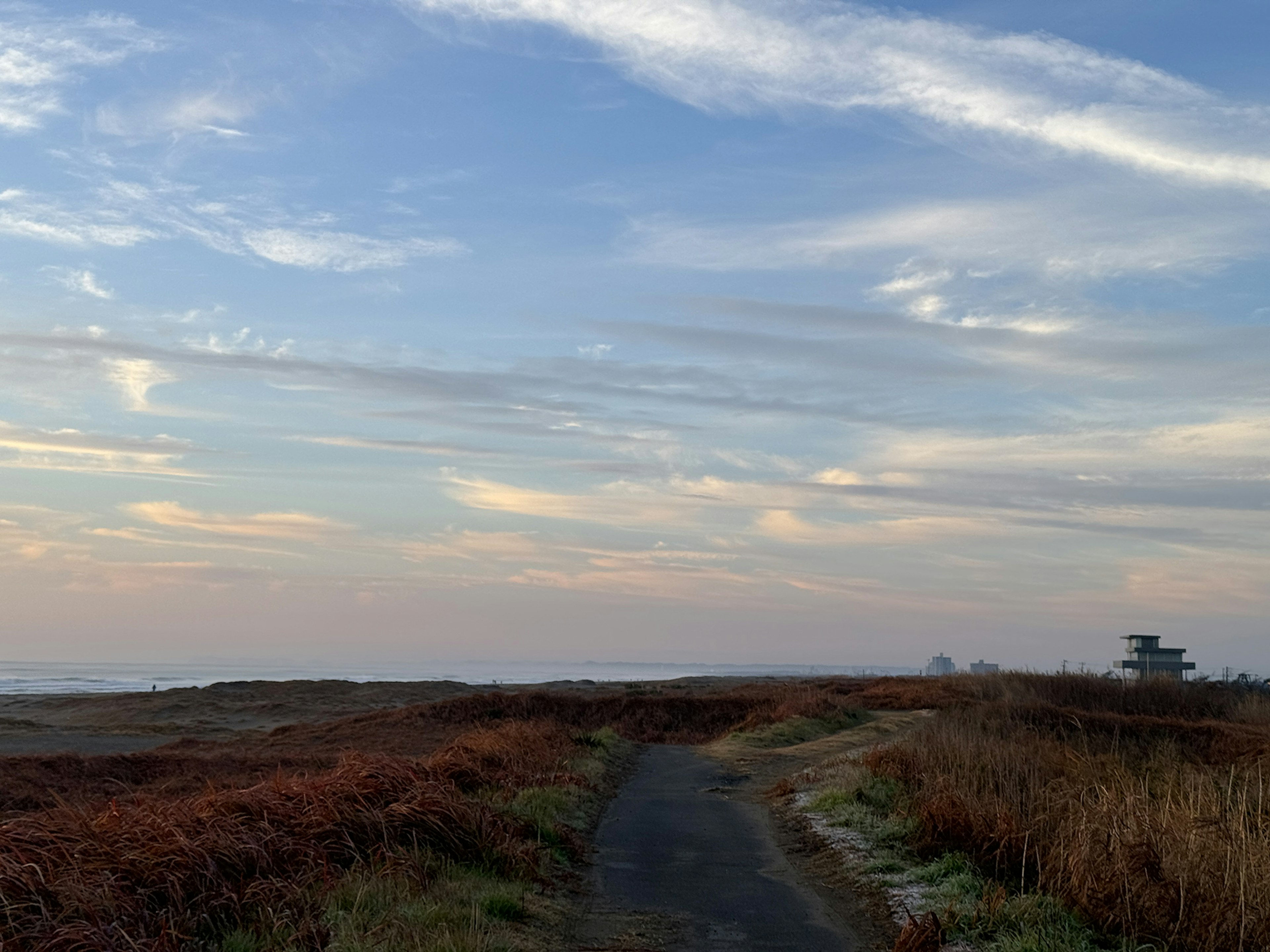 Camino serpenteante a través de un campo seco bajo un cielo azul con nubes