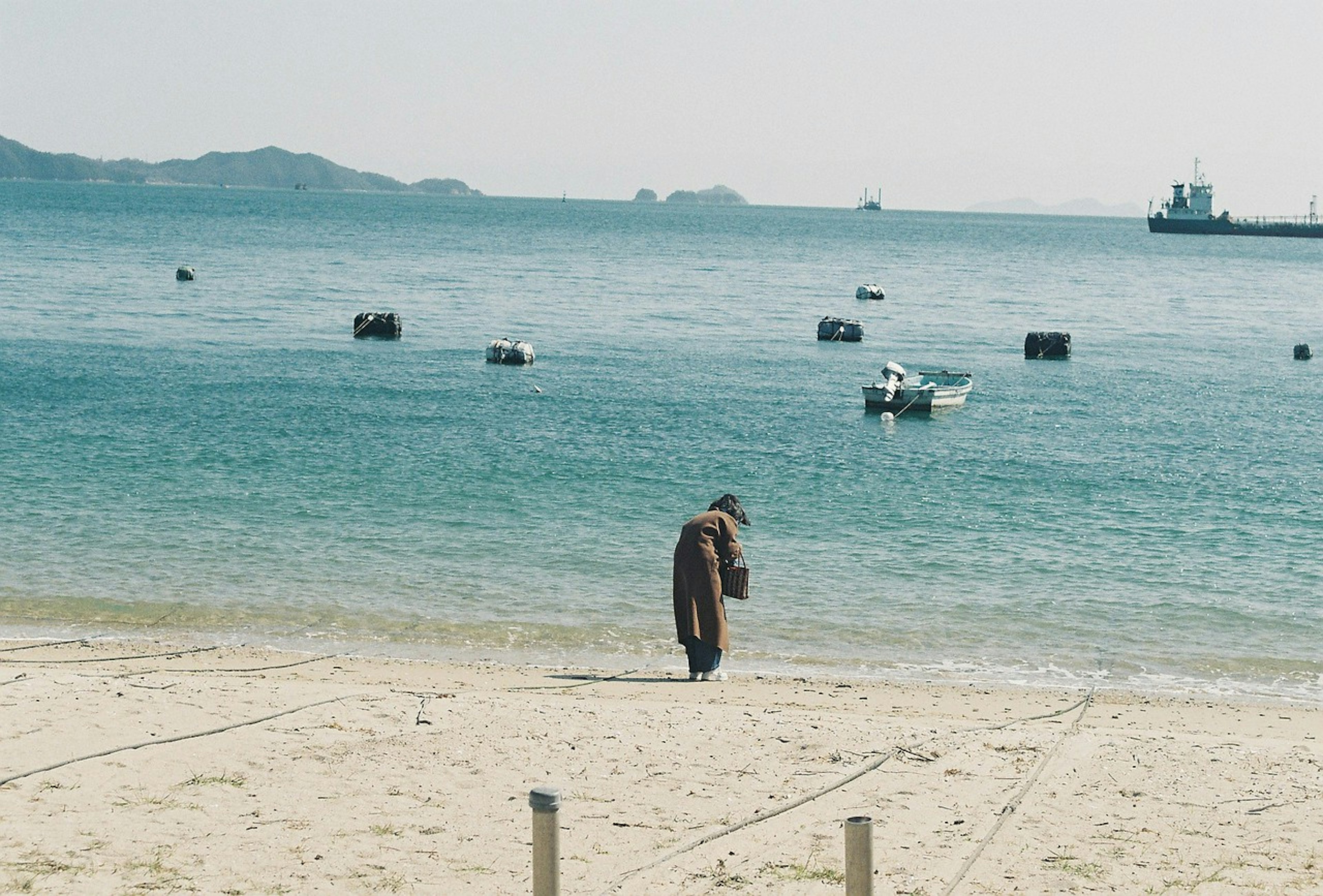 Persona che cammina lungo la spiaggia con acqua calma sullo sfondo