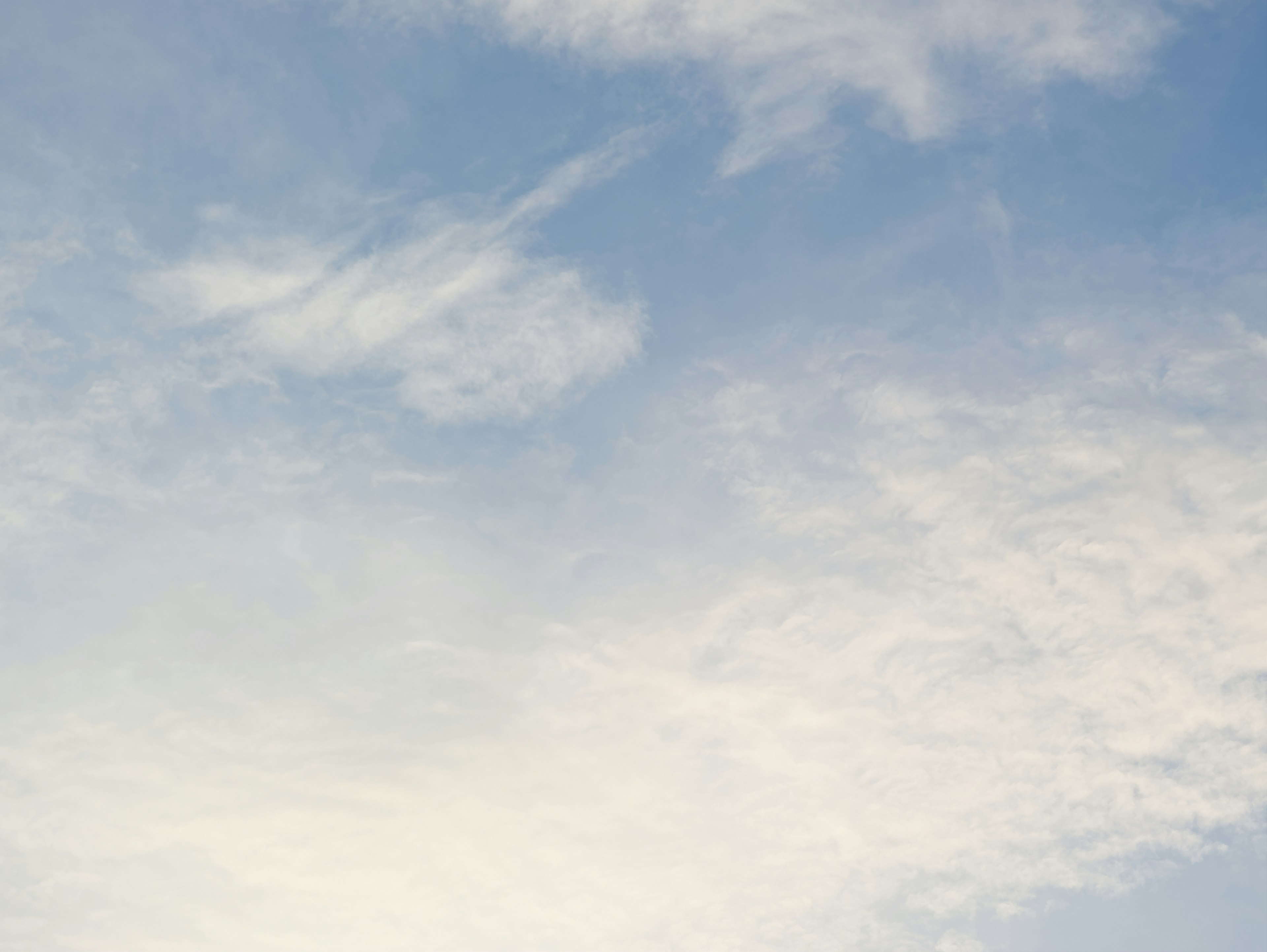 A clear blue sky with wispy clouds