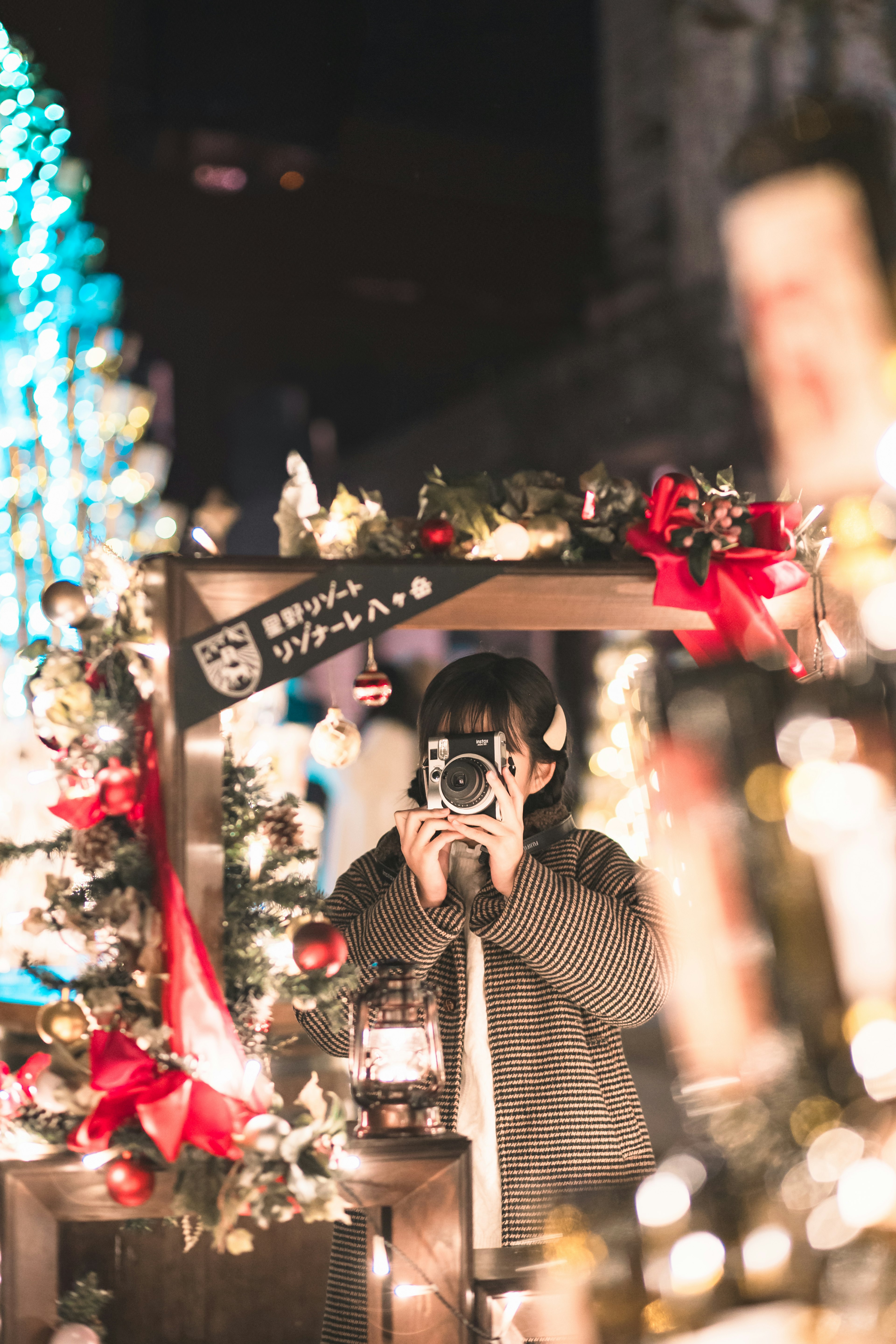 Donna con una macchina fotografica in una scena notturna decorata per Natale