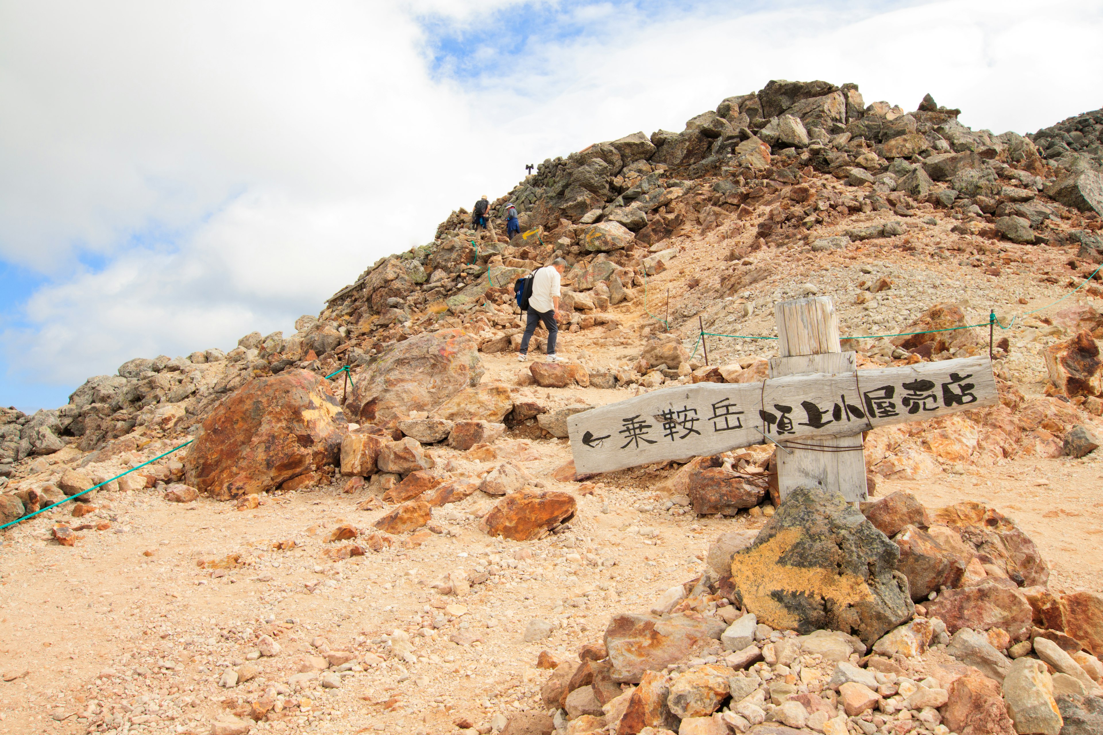 Hikers ascending a mountain trail with a directional sign