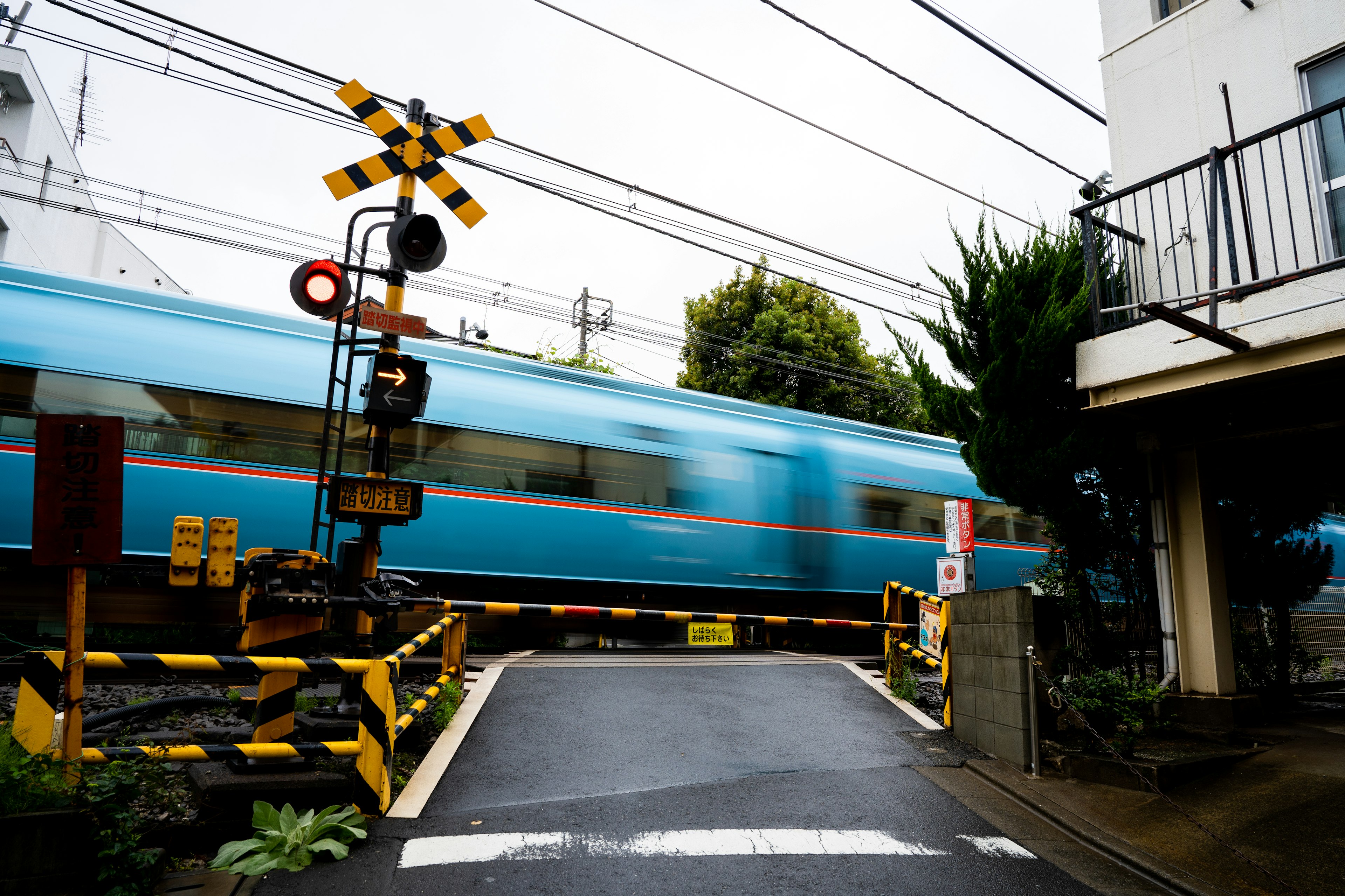 A blue train passing through a railway crossing