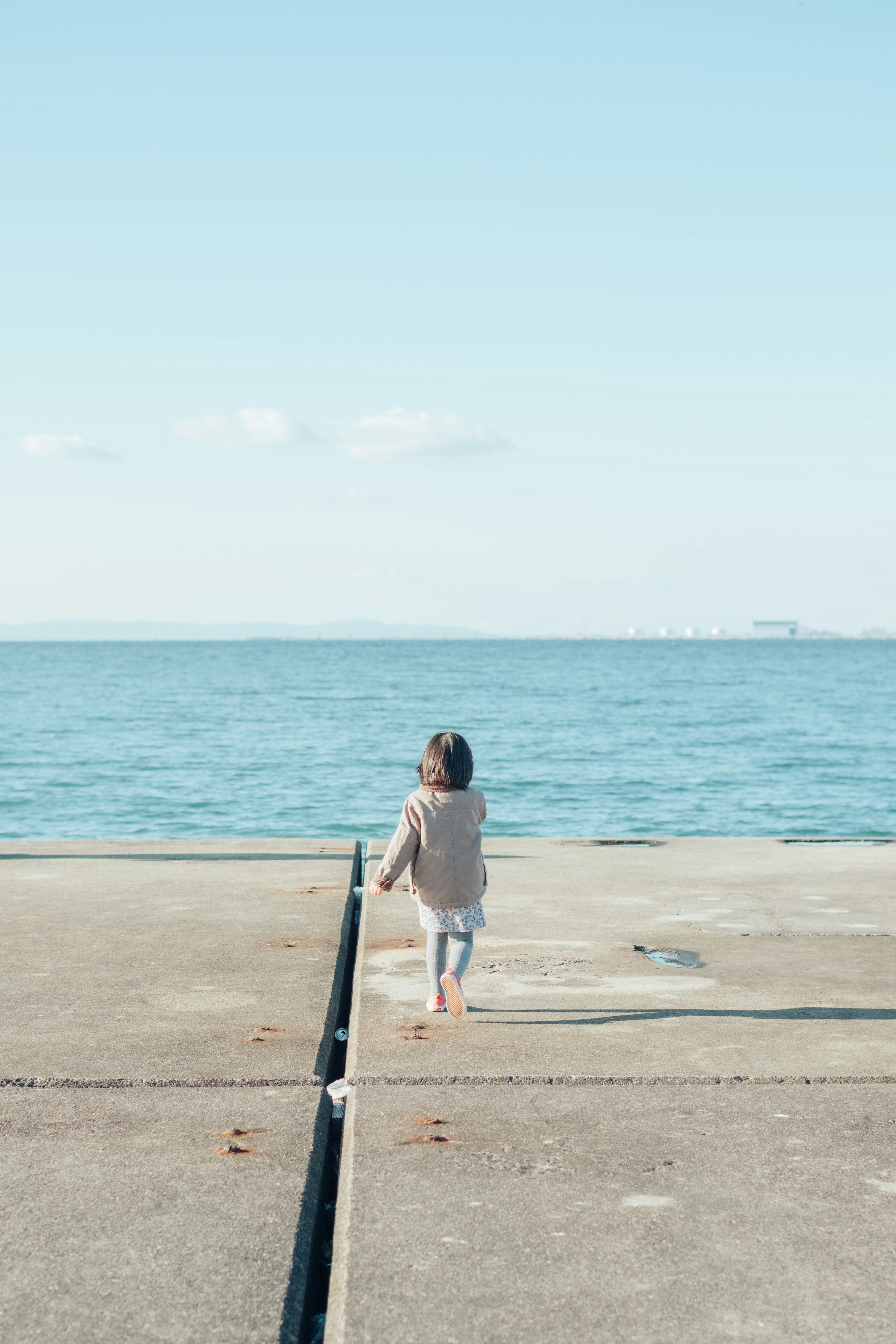 海に向かって歩く子供の後ろ姿