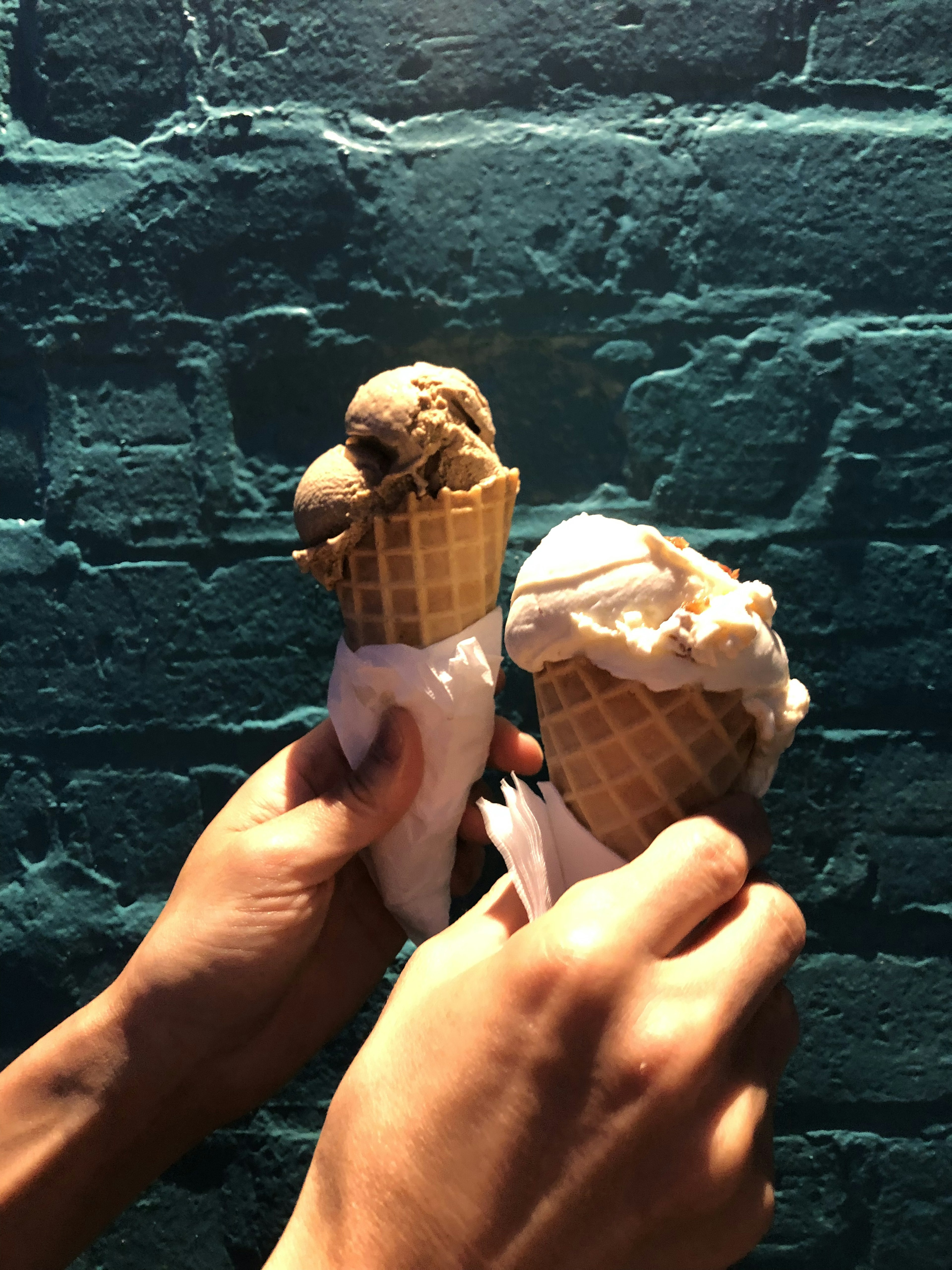 Deux cornets de glace tenus à la main avec différentes saveurs