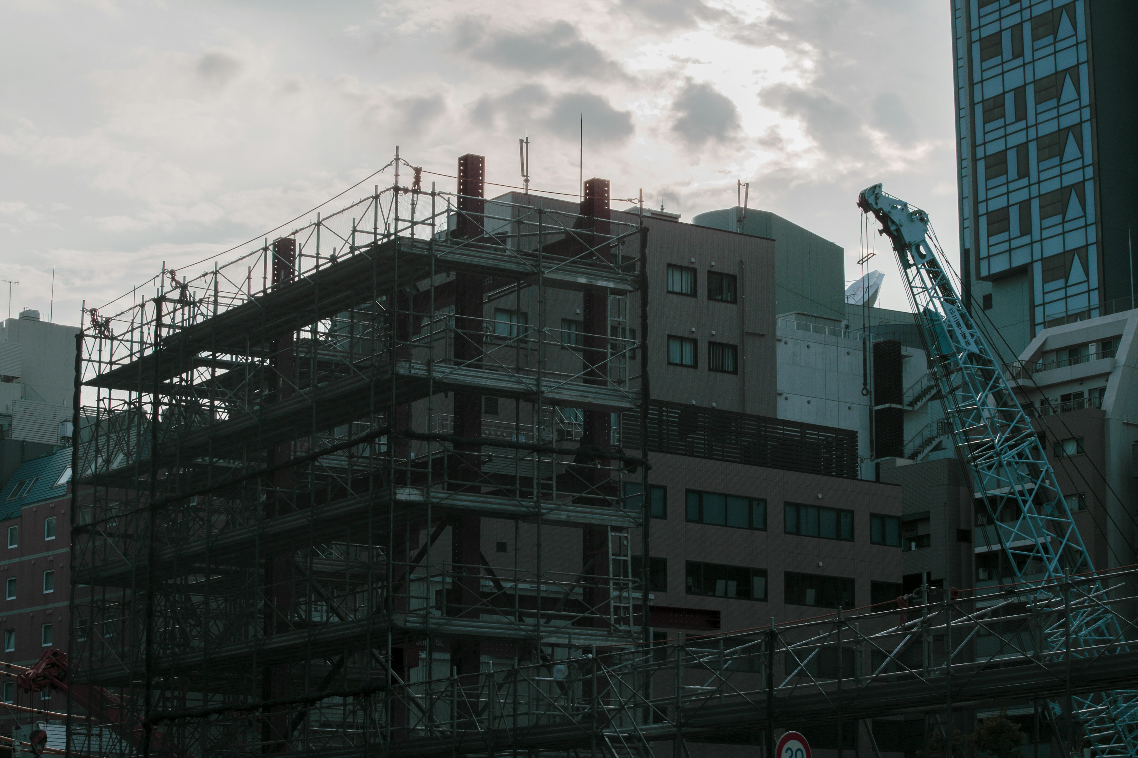 Urban scene featuring a construction site with scaffolding and a crane